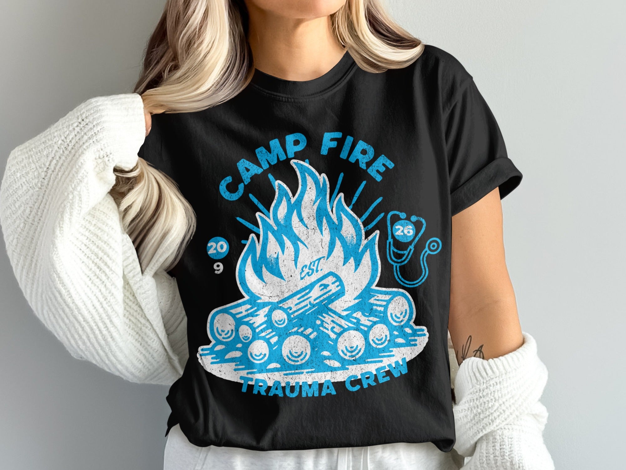 Black t-shirt with a blue campfire graphic and "Camp Fire Trauma Crew" text.