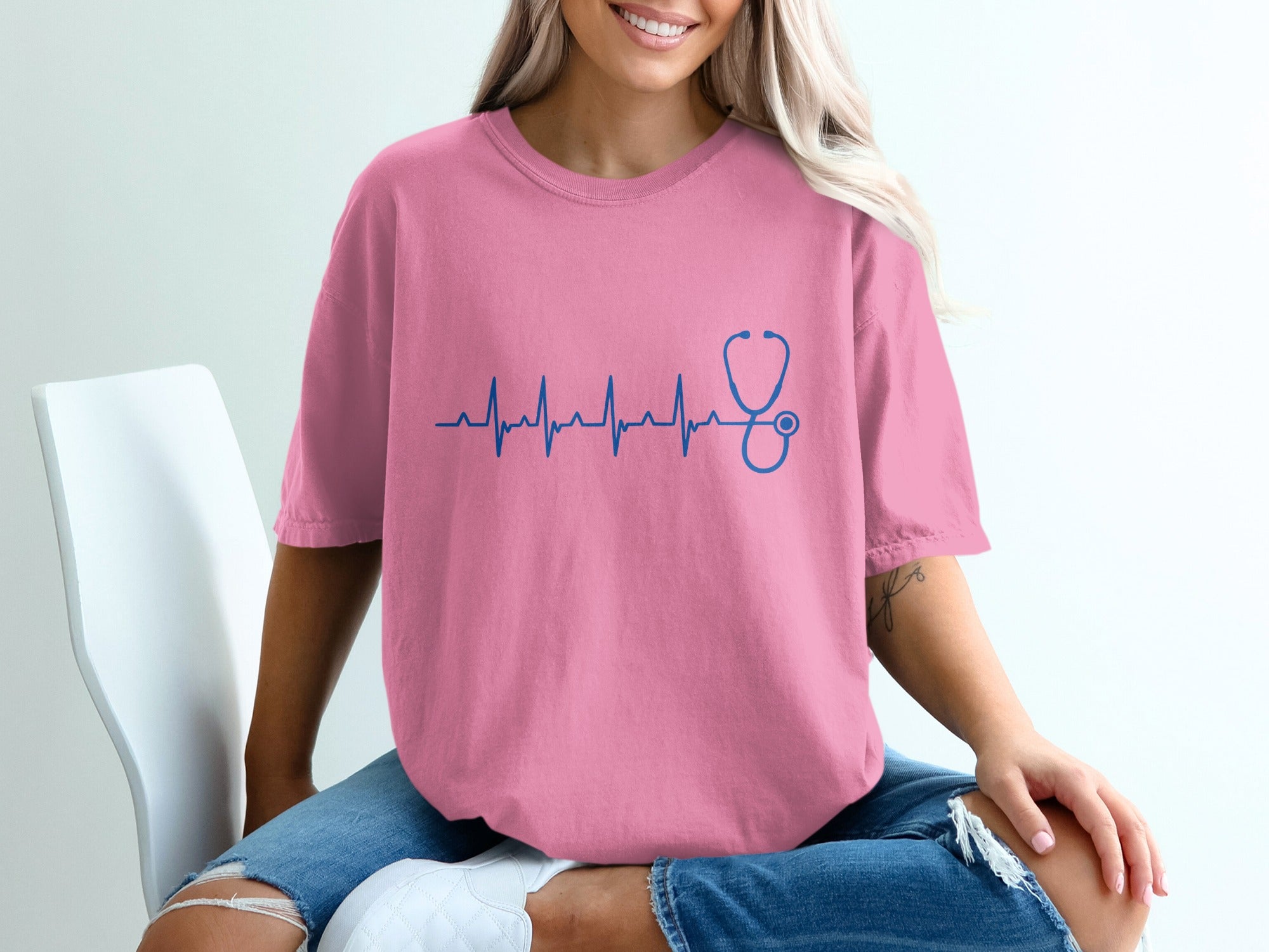 Pink t-shirt with a blue stethoscope and heartbeat graphic.