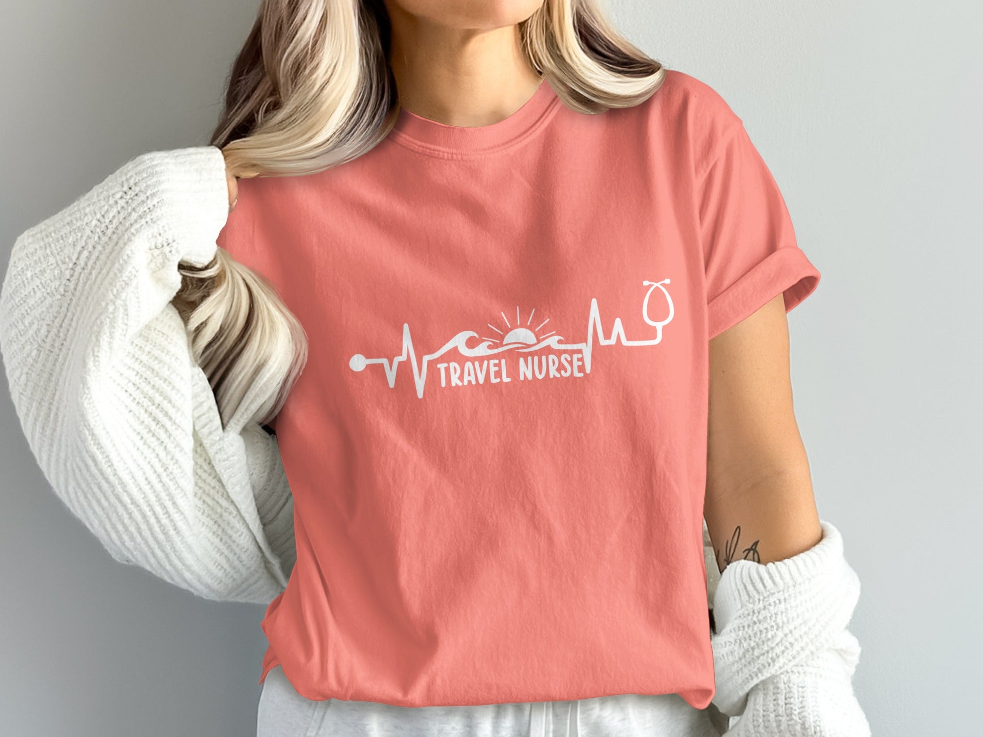 Coral t-shirt with "Travel Nurse" text, heartbeat, waves, and sunrise graphic.