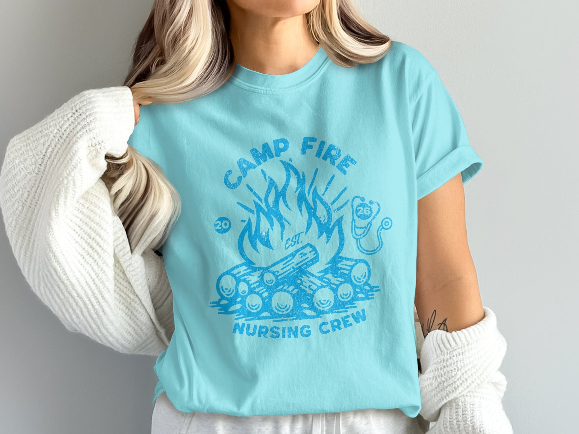 Light blue t-shirt with campfire graphic and "CAMP FIRE NURSING CREW EST 2020" text.