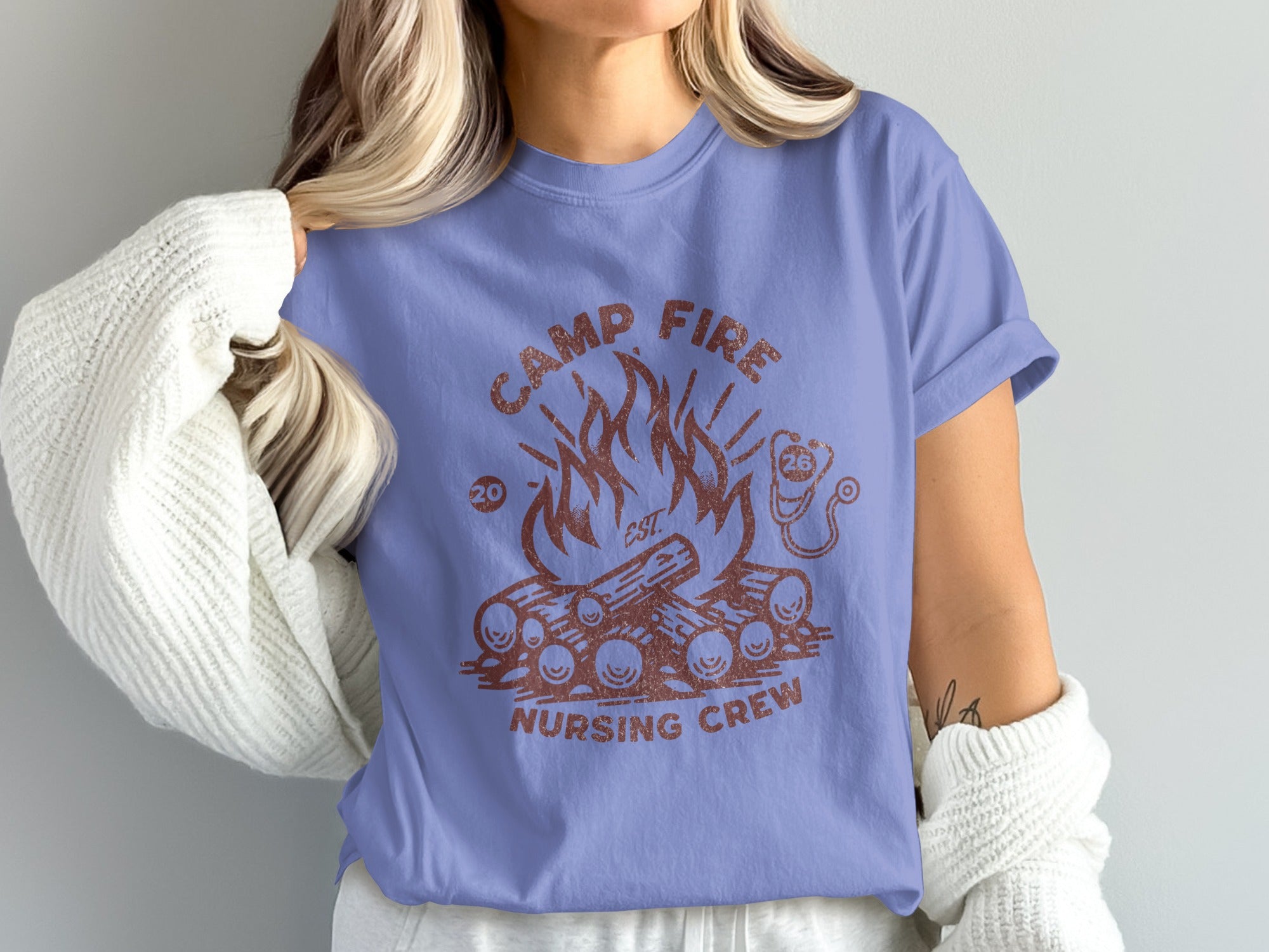 Camp Fire Nursing Crew graphic on a lavender t-shirt with logs and flames.