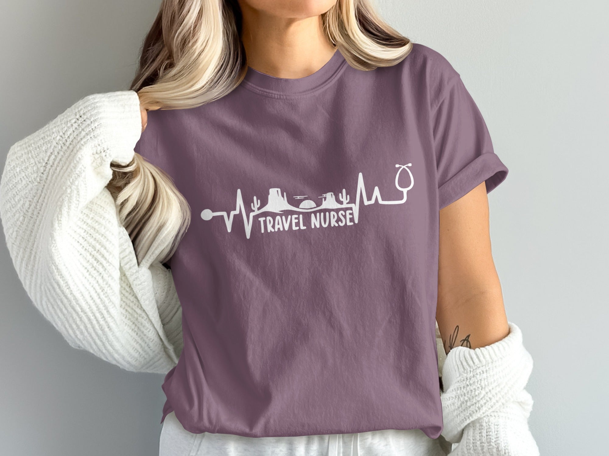Purple t-shirt with travel nurse graphic featuring heartbeat and desert landscape.