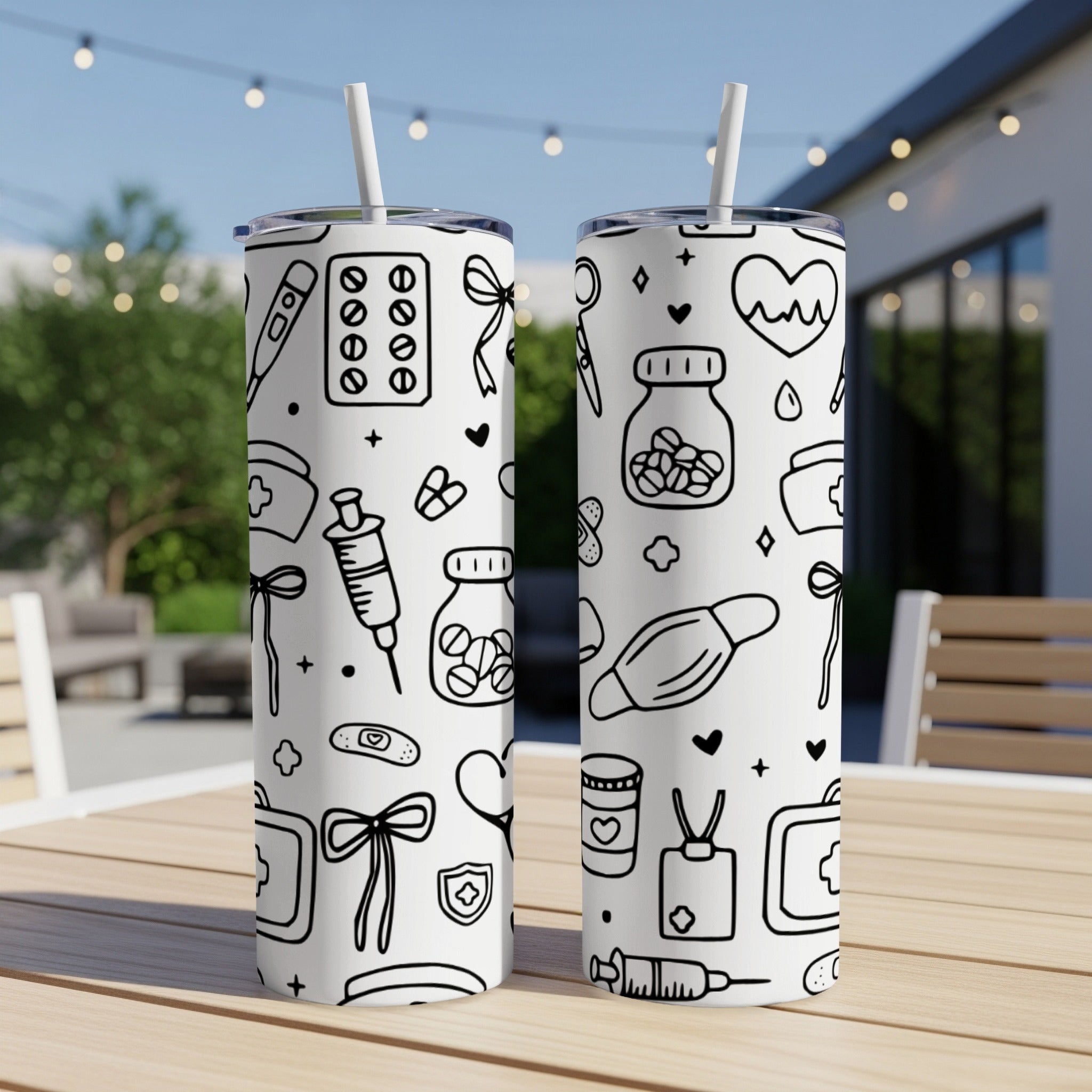 Two tumblers with black and white medical icons on a patio table.