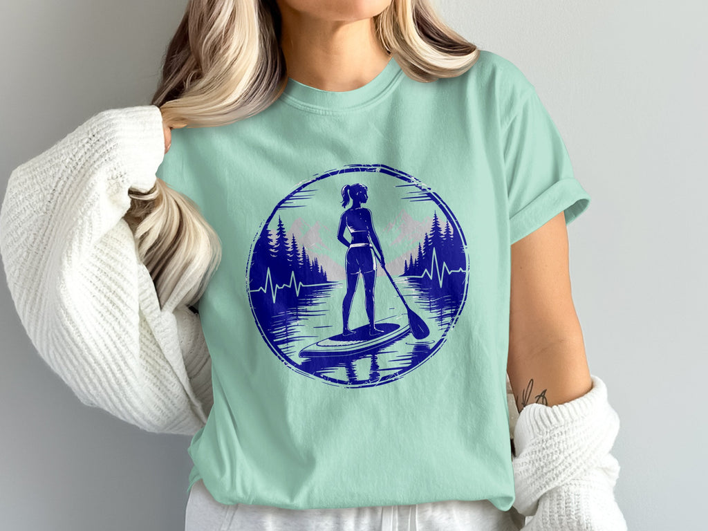 Woman paddleboarding in a circular graphic with trees and mountains.