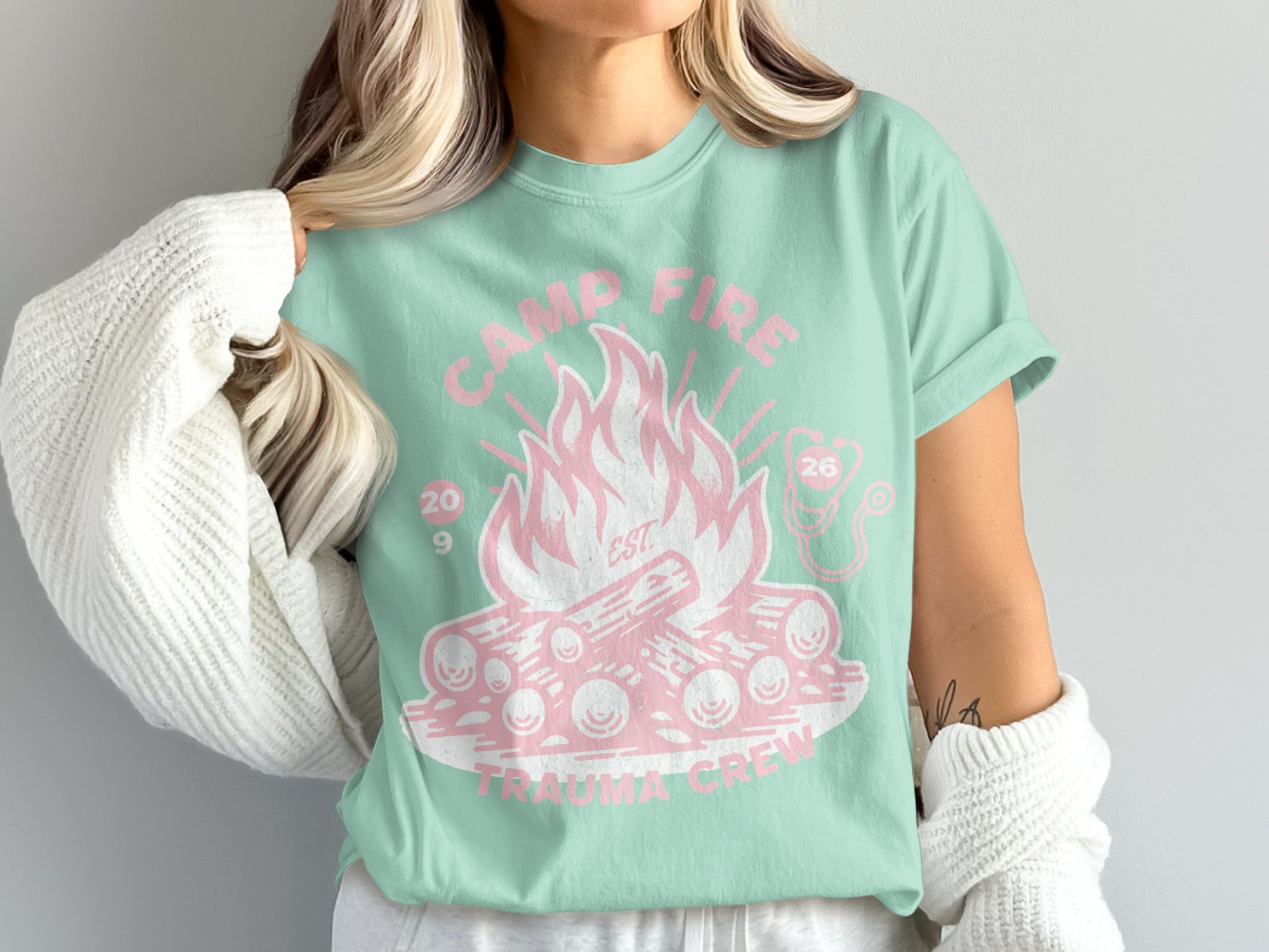 Mint t-shirt with pink campfire graphic and text "Camp Fire Trauma Crew 209 26".