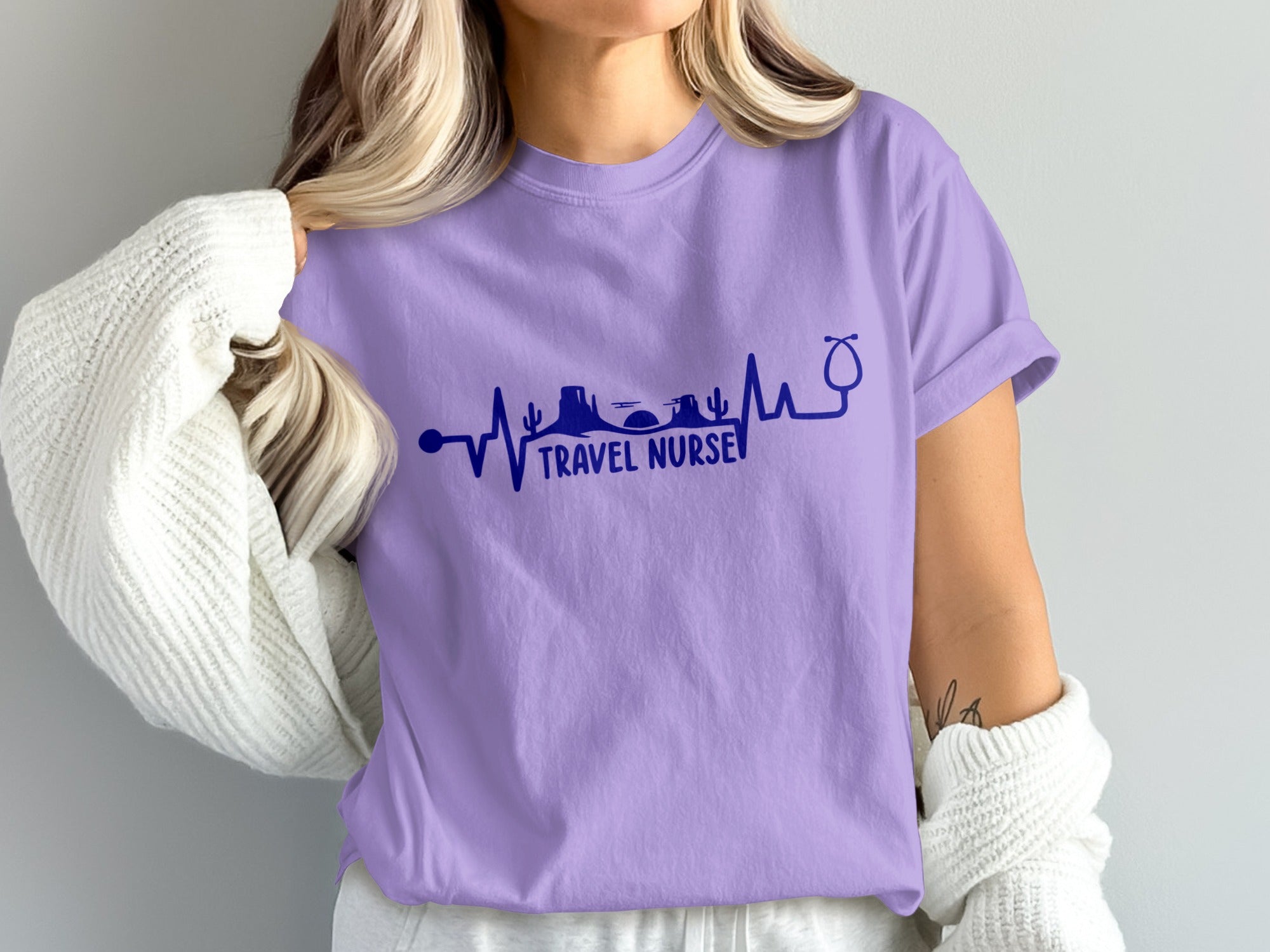Purple t-shirt with a heartbeat line design featuring mountains, desert, and stethoscope.