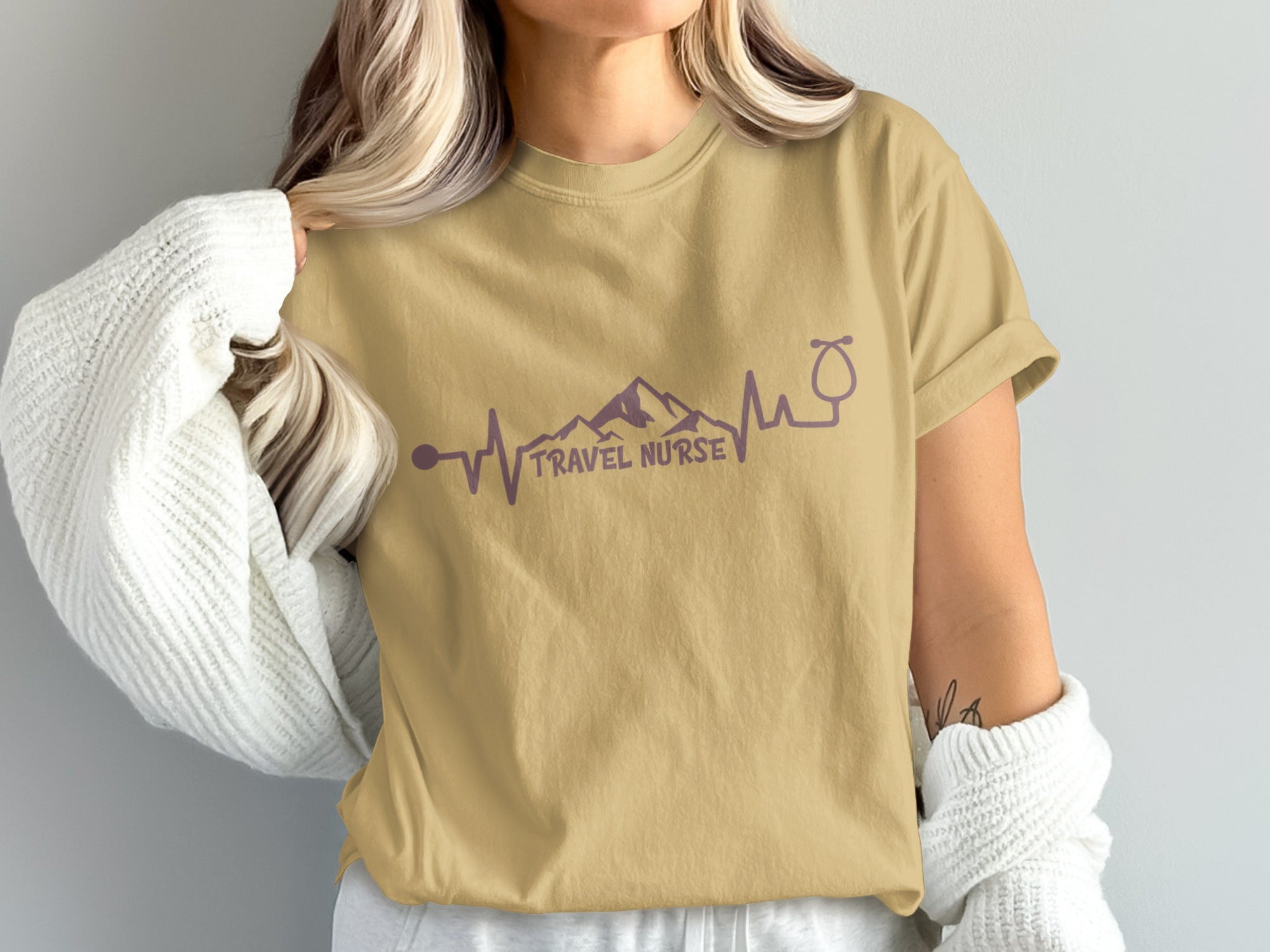 Tan t-shirt with purple mountain heartbeat and stethoscope graphic, "TRAVEL NURSE" text.