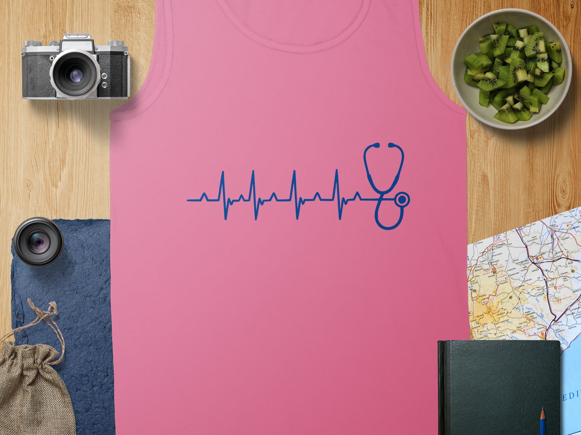 Pink tank top with blue stethoscope heartbeat design, flat lay.