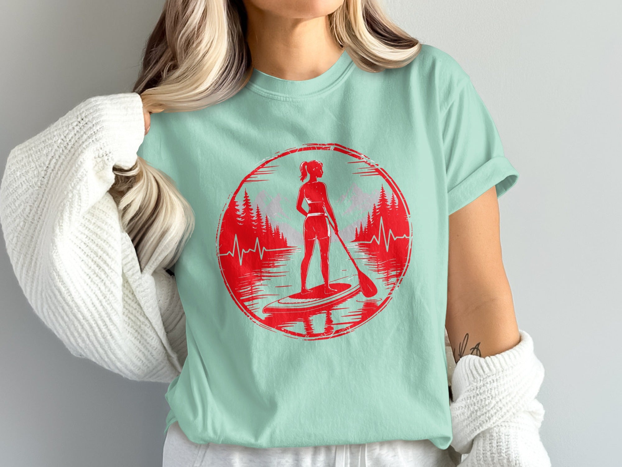 Woman on paddleboard with trees and heartbeat graphic.