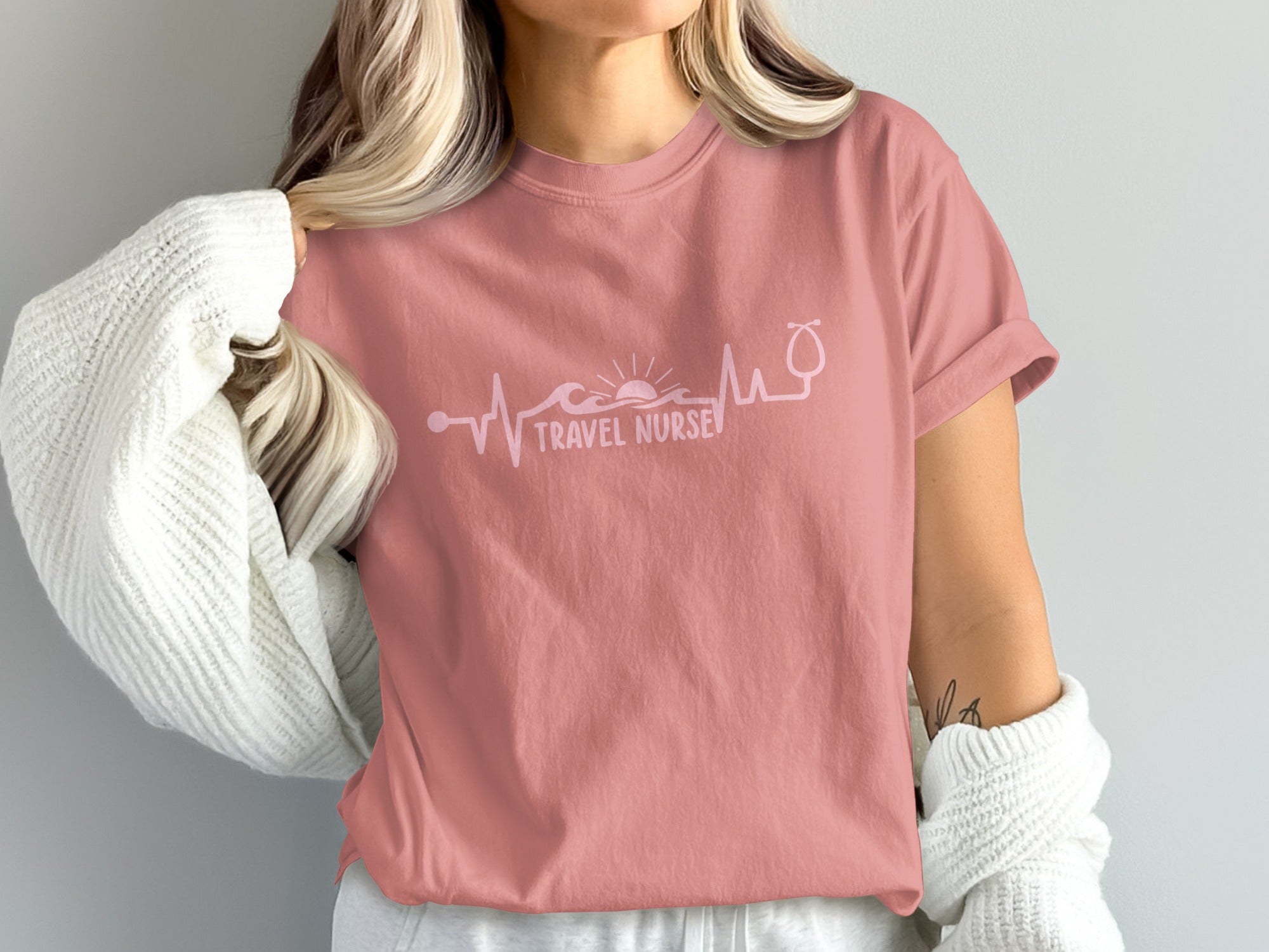 Pink t-shirt with "Travel Nurse" text and heartbeat waveform with sun.