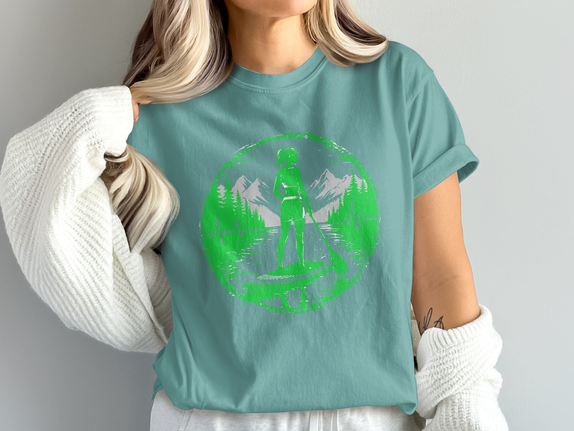 Green circular graphic with paddleboarder, mountains, and trees.
