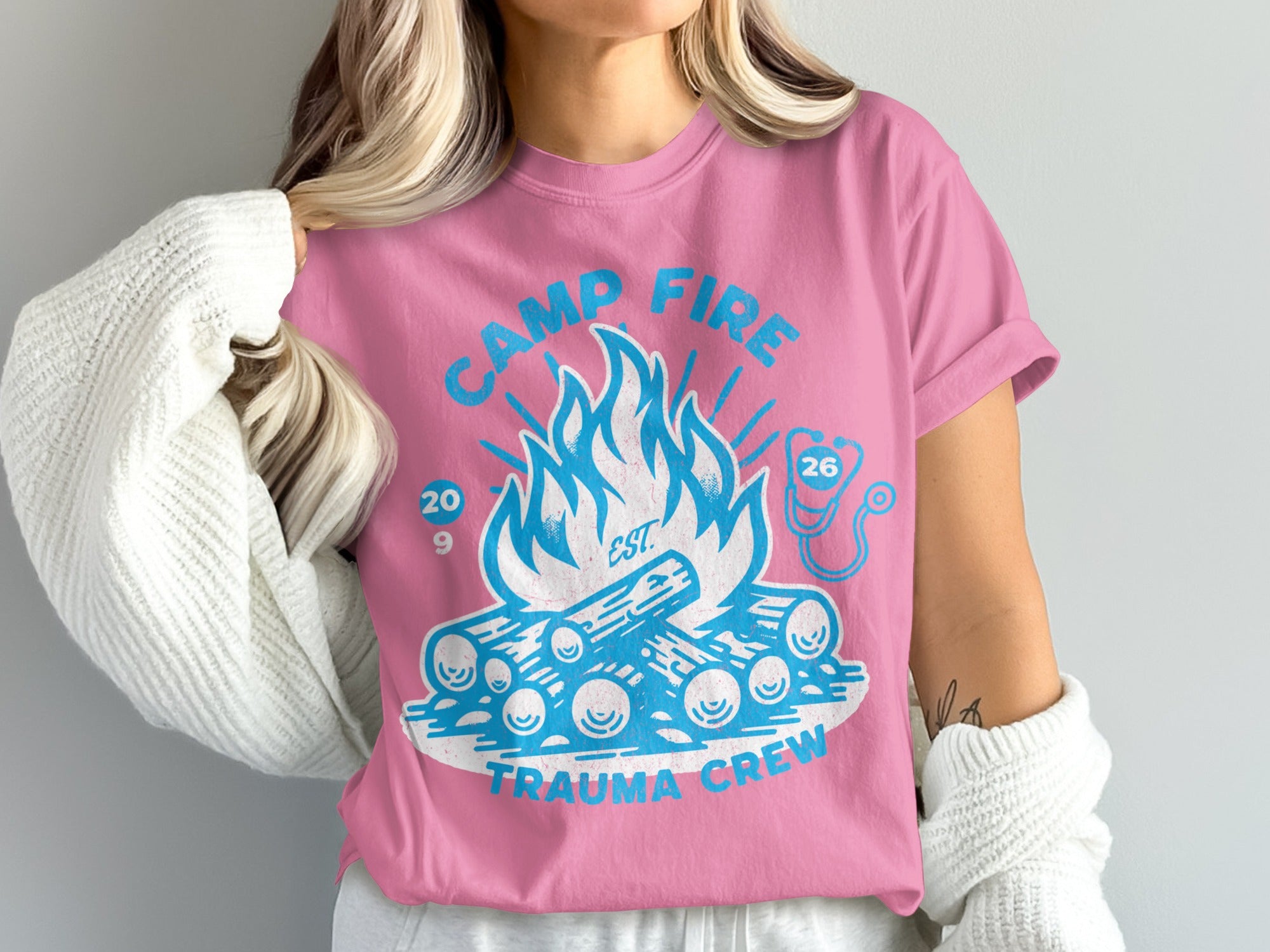Pink t-shirt with campfire graphic, "Camp Fire Trauma Crew," and stethoscope.