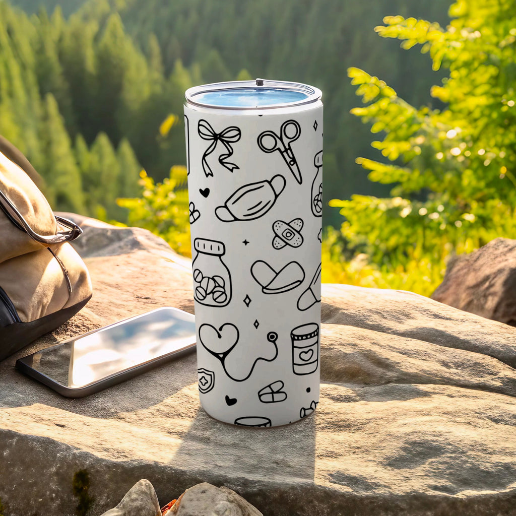 White tumbler with medical-themed line art illustrations, resting outdoors.