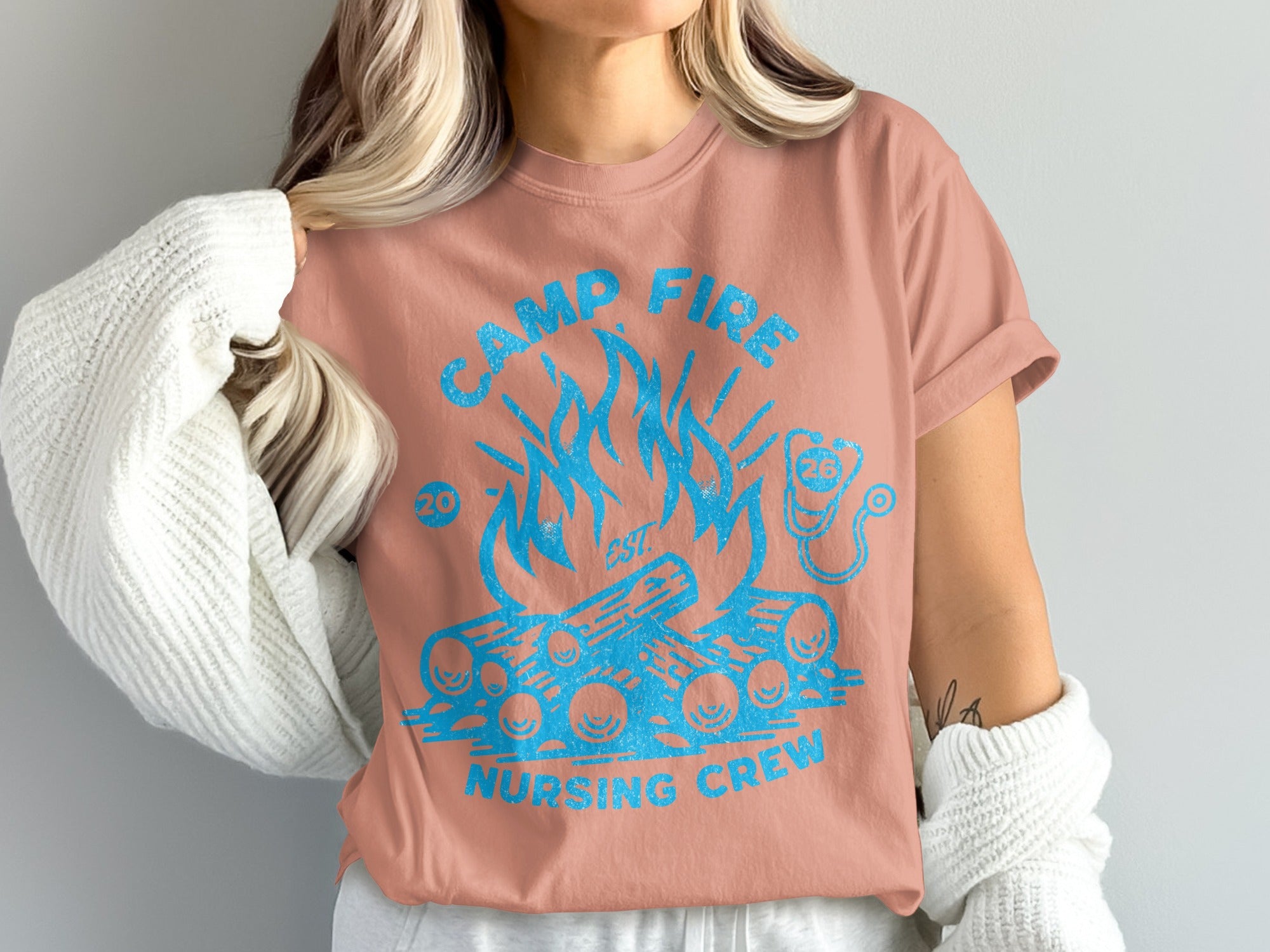 Salmon t-shirt with blue "Camp Fire Nursing Crew" graphic and stethoscope.