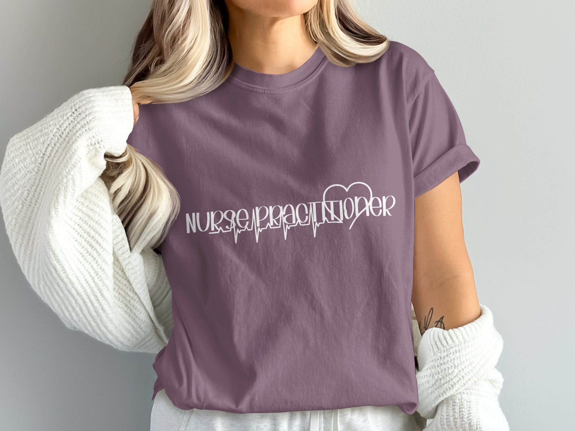 Nurse Practitioner text with heartbeat graphic on a purple t-shirt.