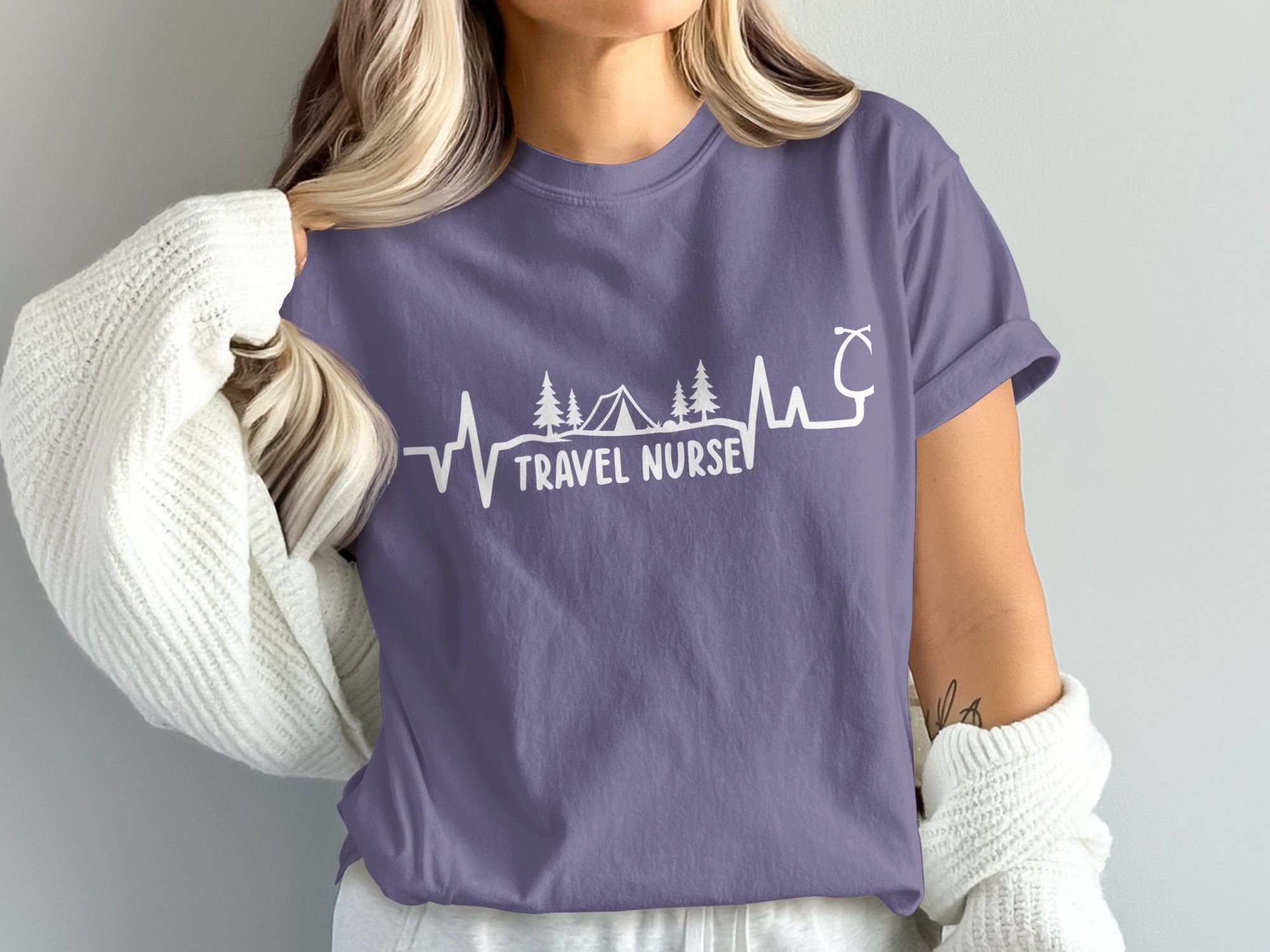 Purple t-shirt with "Travel Nurse" text and heartbeat, tent, and trees design.