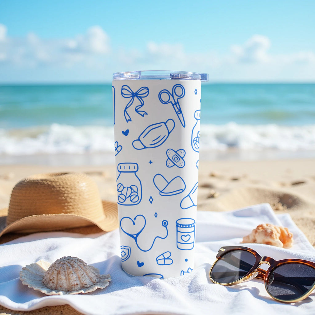 White tumbler with blue medical icons on a beach.