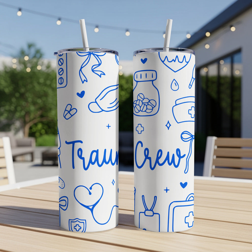 Two blue and white "Trauma Crew" tumblers with medical icons on a patio table.