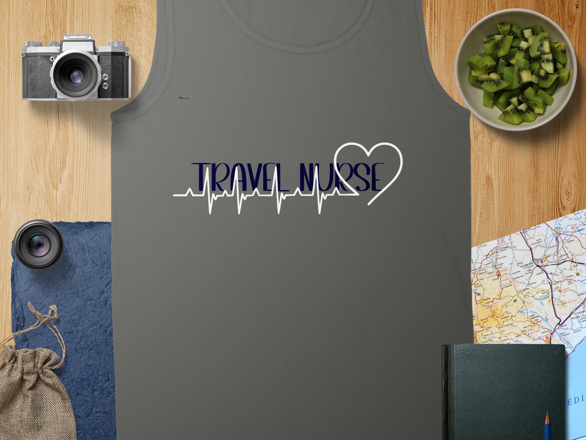 Grey tank top with "TRAVEL NURSE" electrocardiogram heart design, camera, map, and kiwi slices.