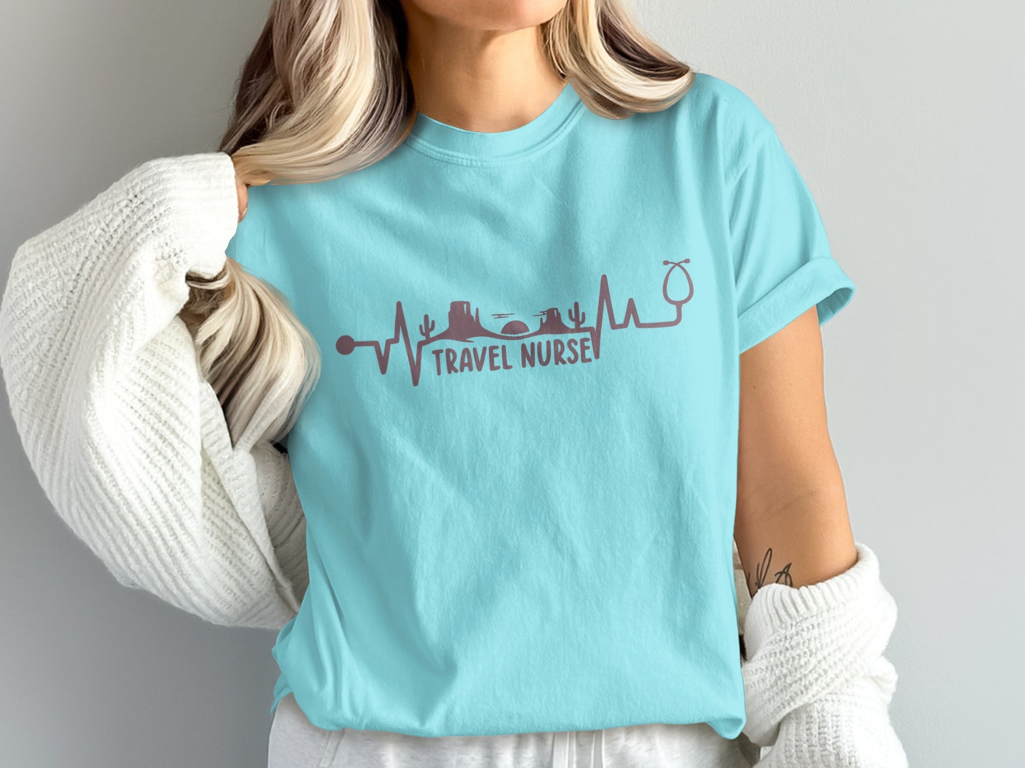 Light blue t-shirt with "Travel Nurse" heartbeat graphic and skyline.