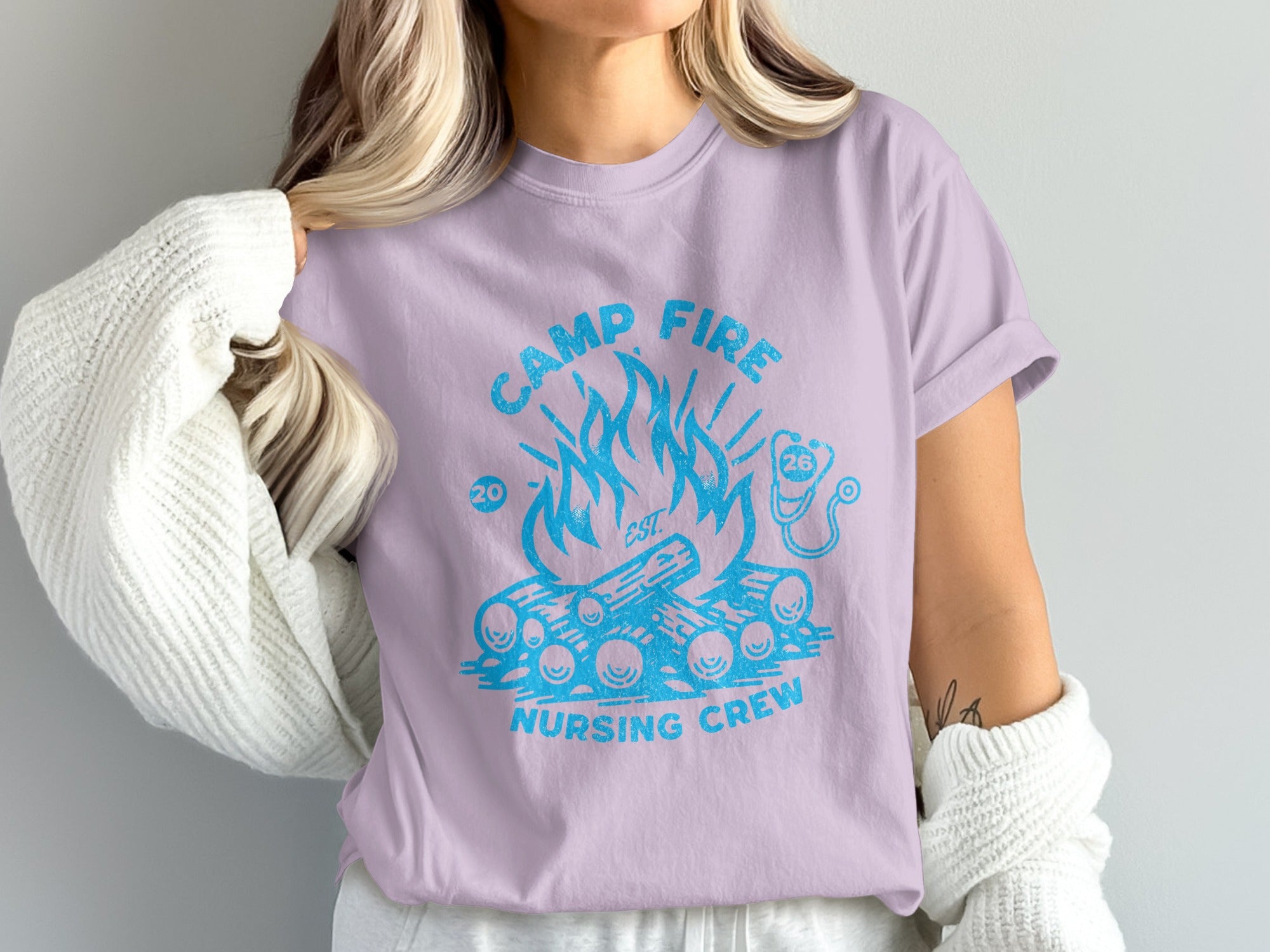 Camp Fire Nursing Crew graphic on a lavender t-shirt with logs and flames.