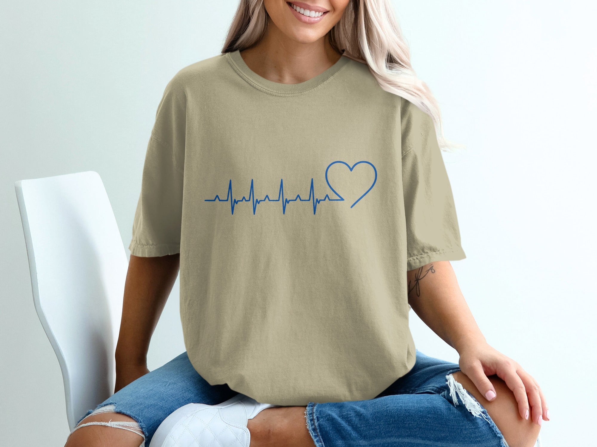 Tan t-shirt with blue heartbeat and heart graphic on chest.