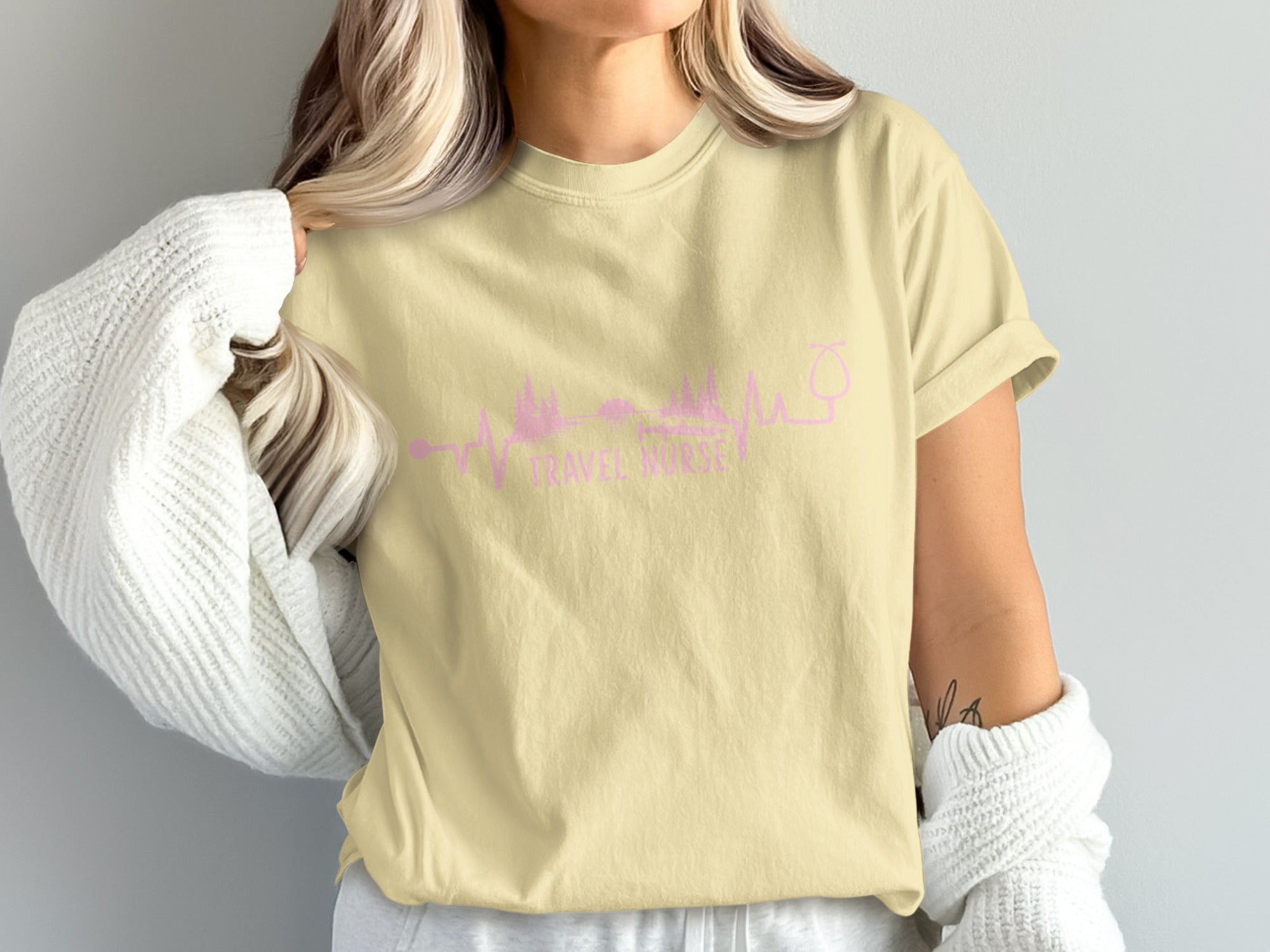 Light yellow t-shirt with pink graphic of a wine glass and mountains, reading "Drink Wine".