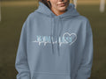 Light blue hoodie with "TRAVEL NURSE" text and heart-shaped heartbeat line.
