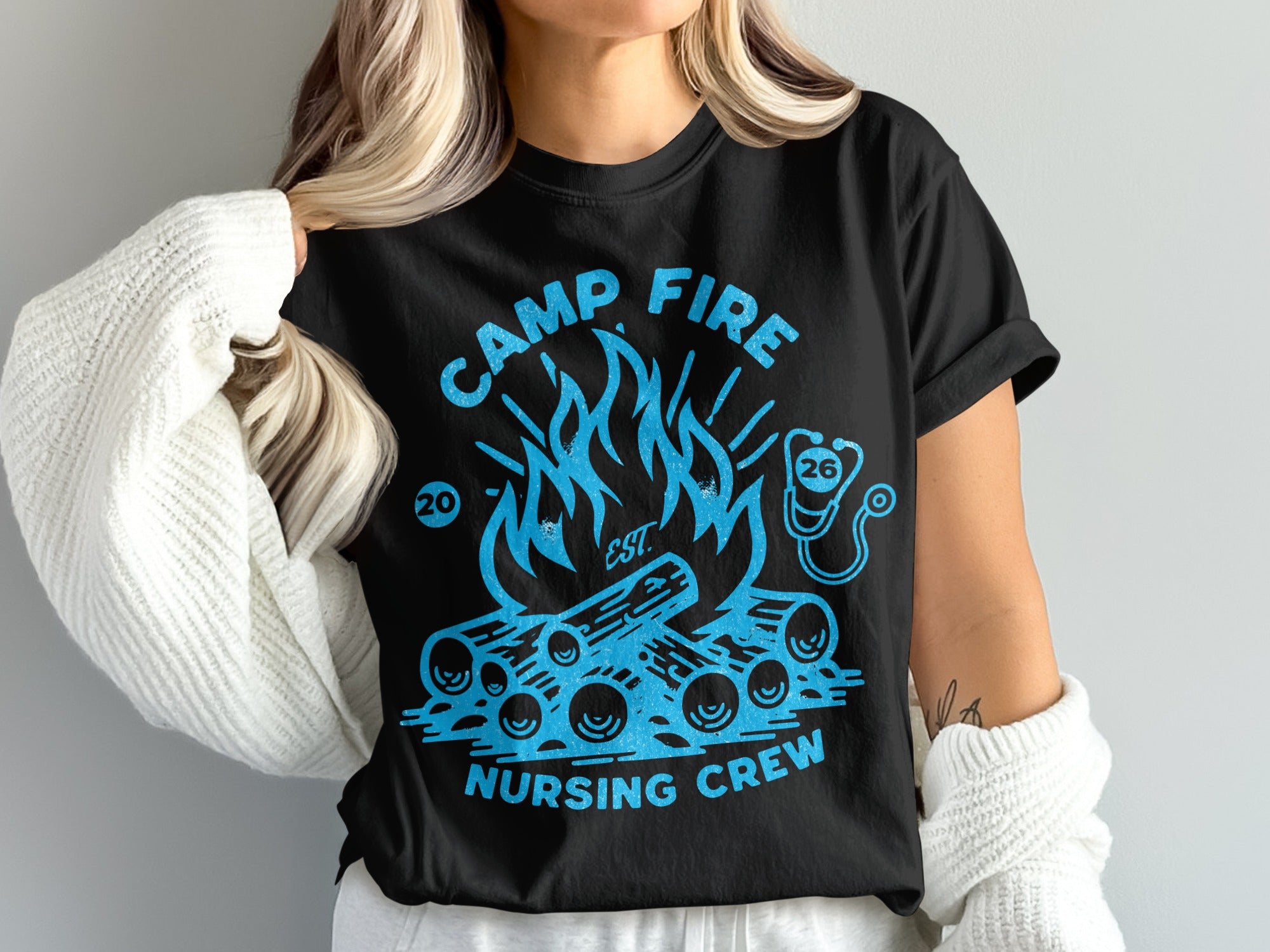 Black t-shirt with blue campfire, logs, and stethoscope graphic, "CAMP FIRE NURSING CREW" text.