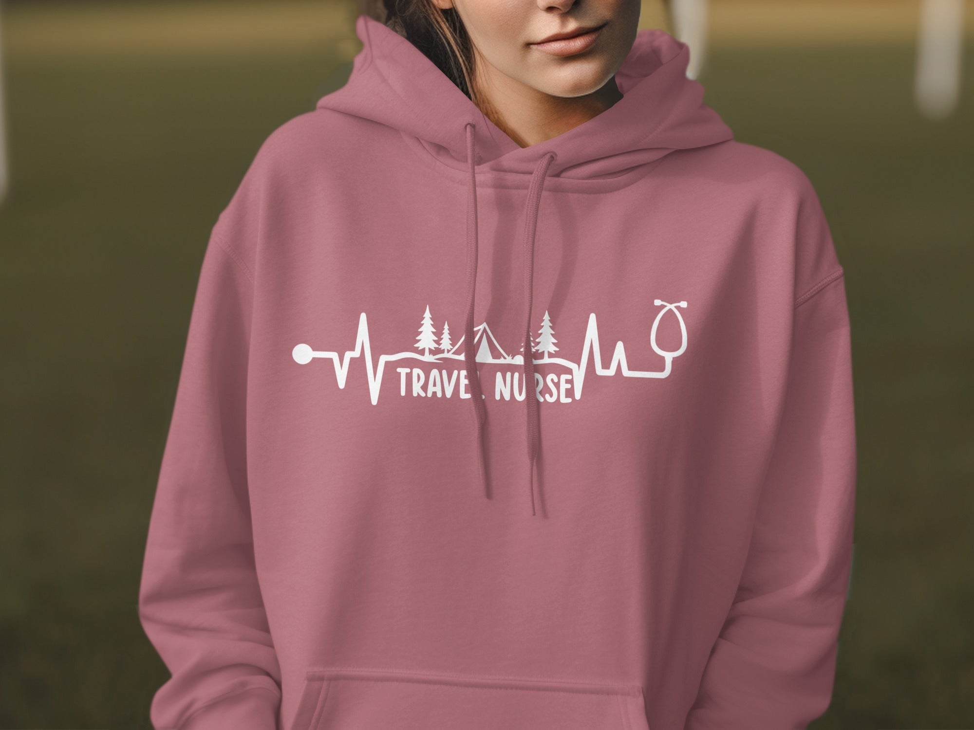 Pink hoodie with a white graphic of a heartbeat line, trees, tents, and stethoscope.