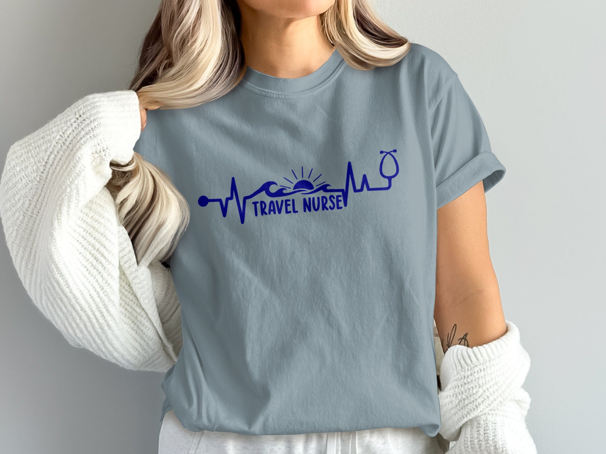 Blue t-shirt with "TRAVEL NURSE" text, waves, and stethoscope in a heartbeat line.