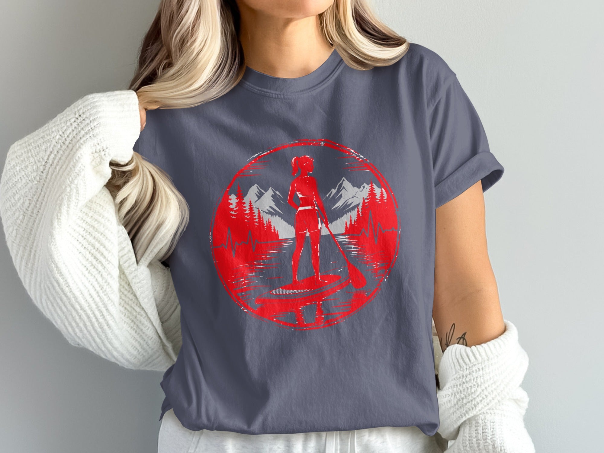 Red circular graphic of a woman stand-up paddleboarding with mountains behind her.
