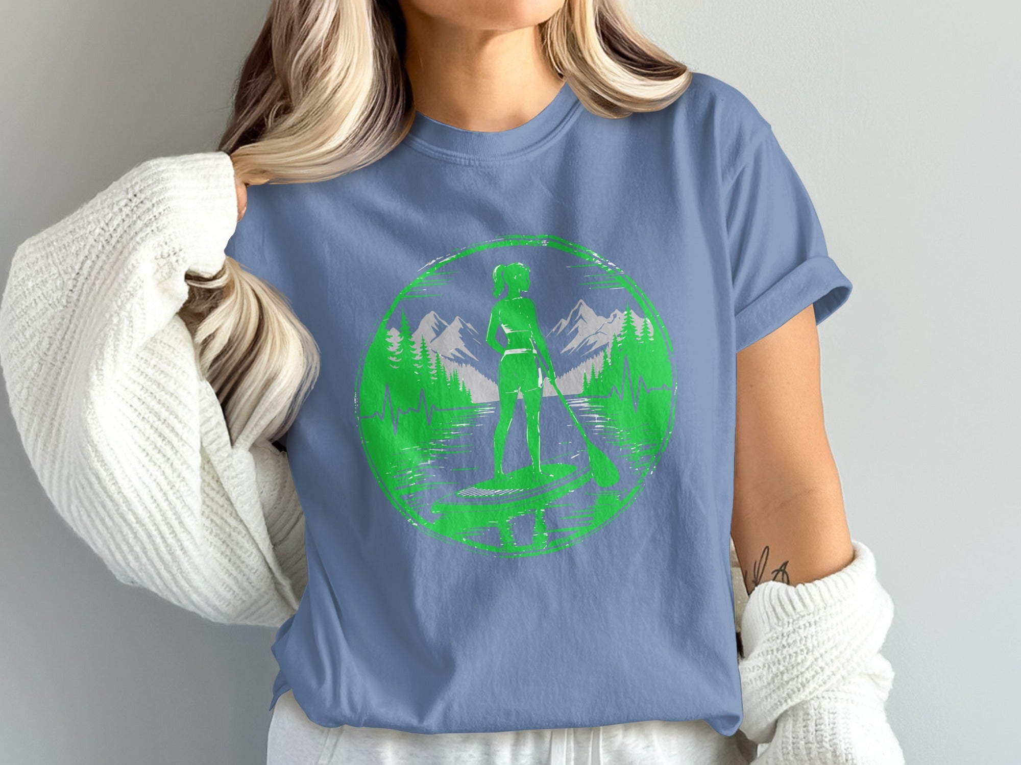 Green graphic of paddleboarder on water with mountains and trees.
