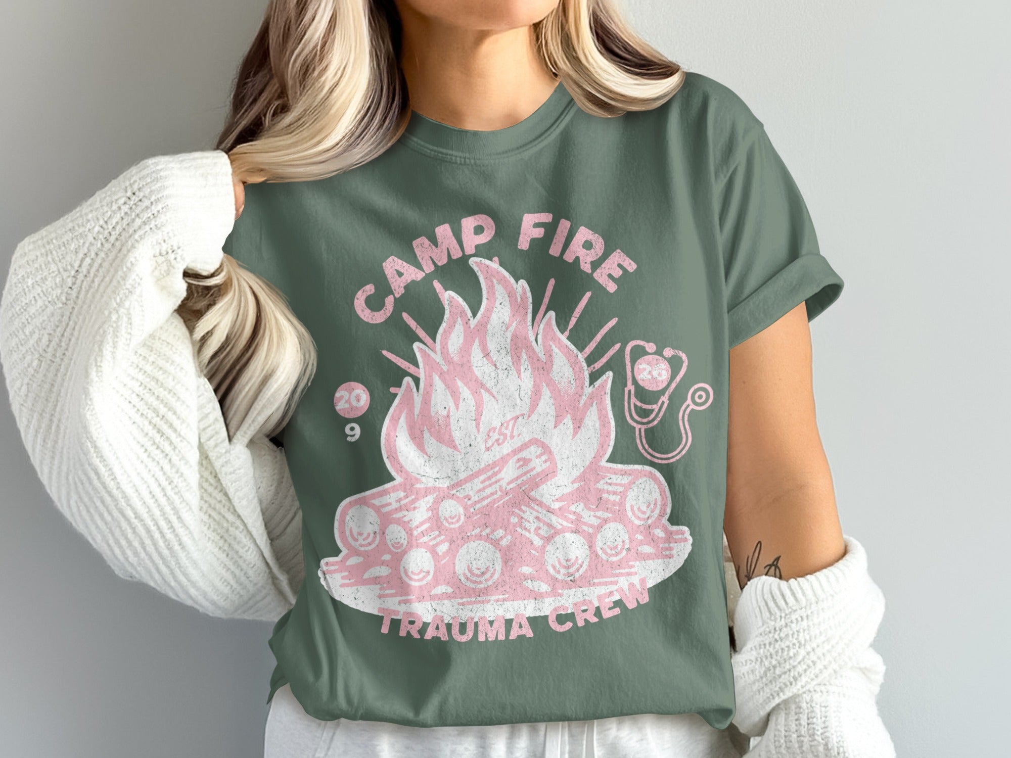 Camp Fire Est. 2009 Trauma Crew t-shirt with a pink campfire graphic.