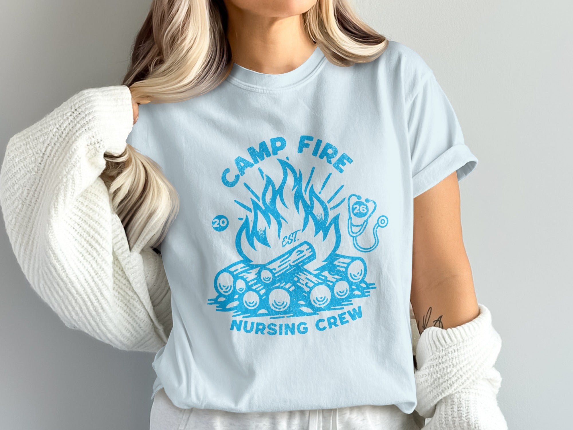 Light blue t-shirt with campfire graphic and "Camp Fire Nursing Crew" text.