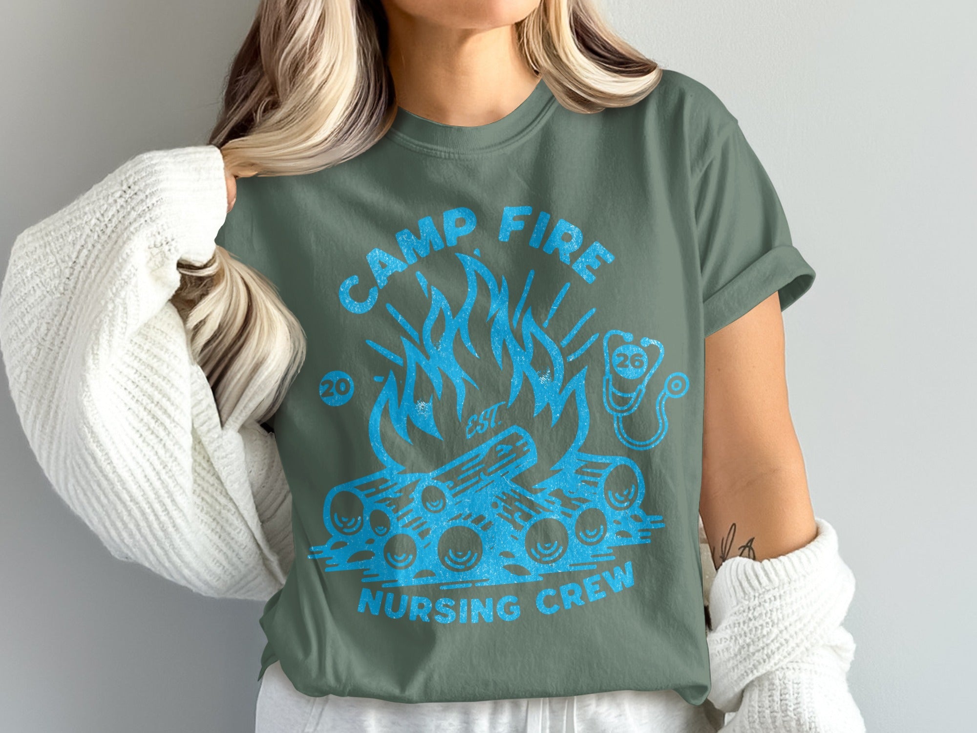Green t-shirt with blue campfire and "CAMP FIRE NURSING CREW" text.