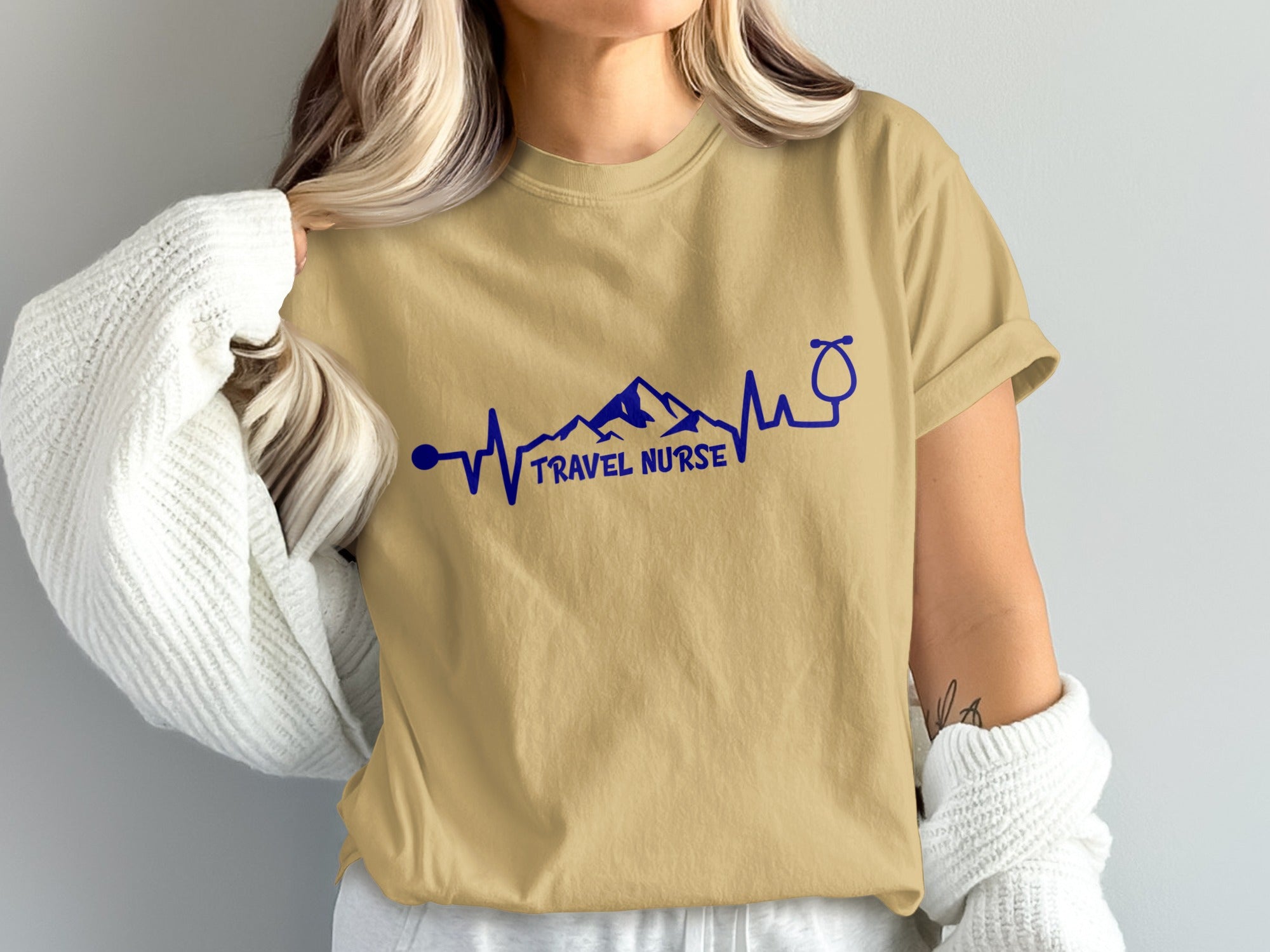 Tan t-shirt with "Travel Nurse" text and mountain, heartbeat, stethoscope graphic.