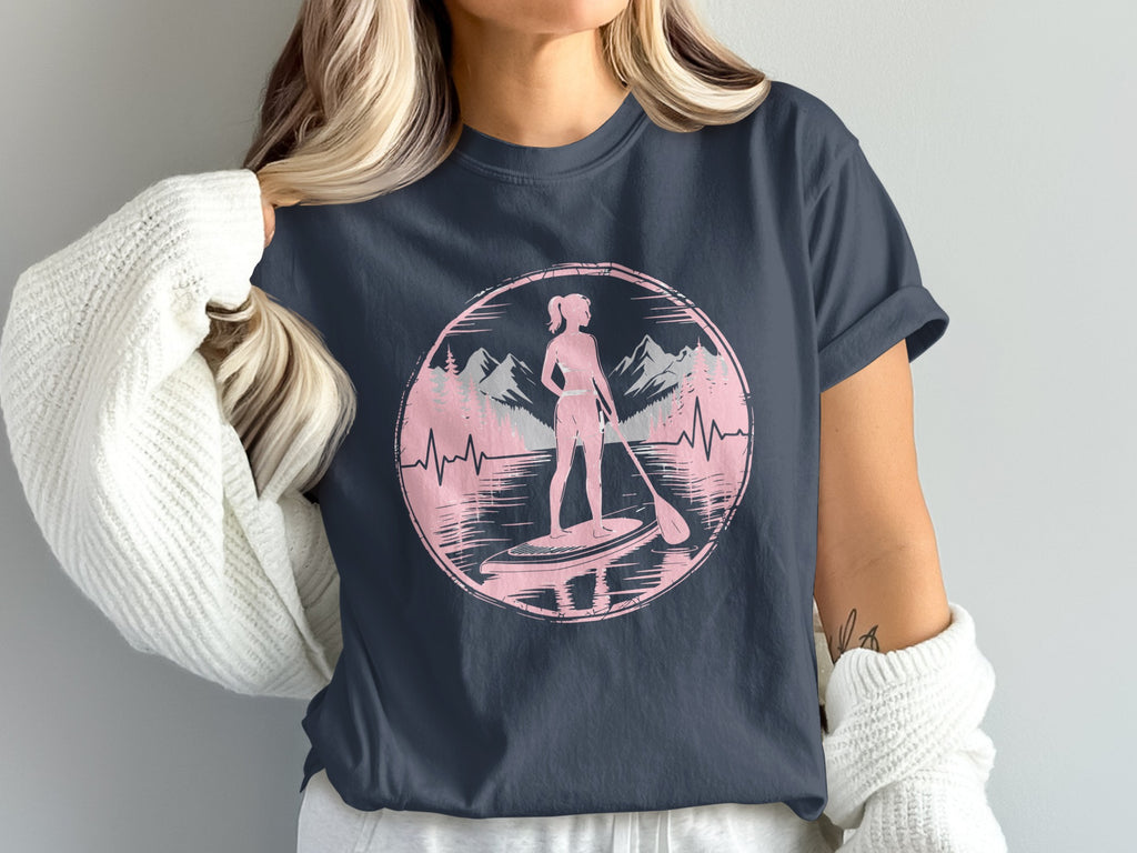 Woman paddleboarding with mountains and trees in a pink circle.
