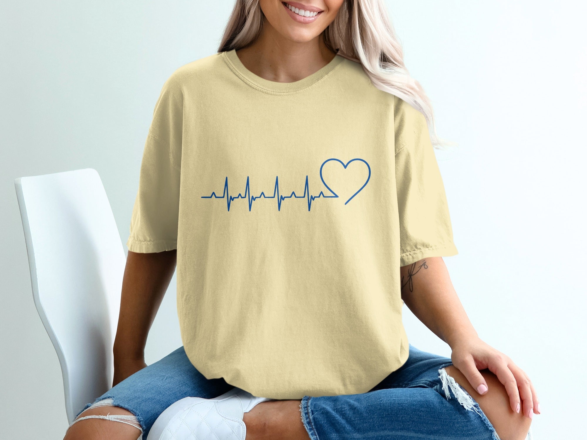Cream t-shirt with blue heart and heartbeat graphic.