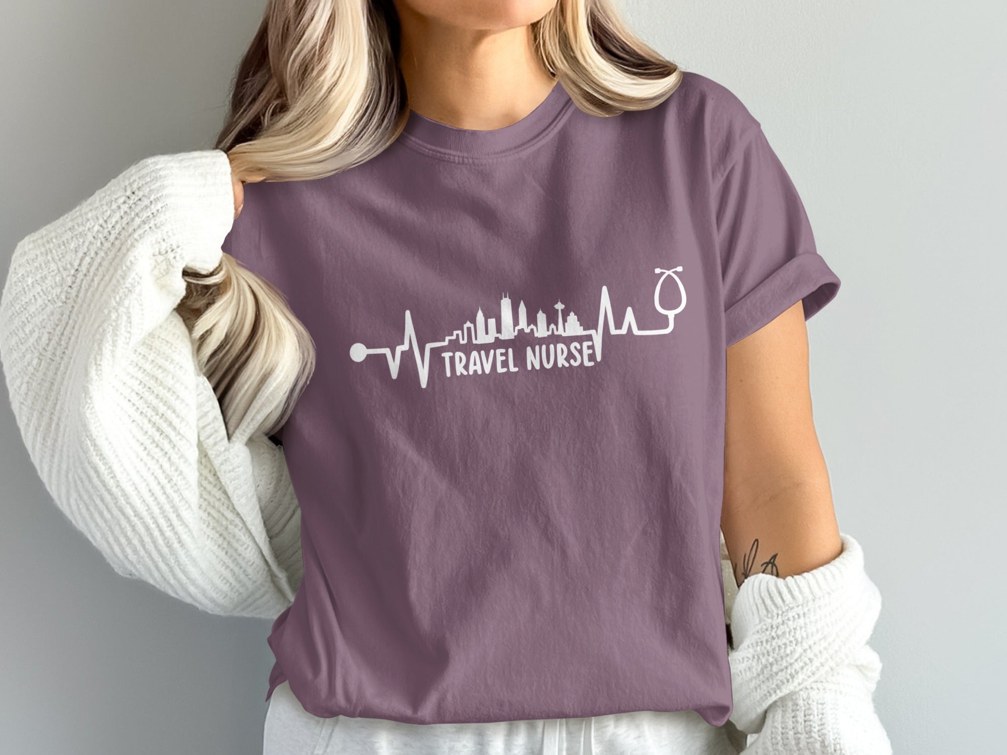 Purple t-shirt with "Travel Nurse" text and a skyline heartbeat graphic.
