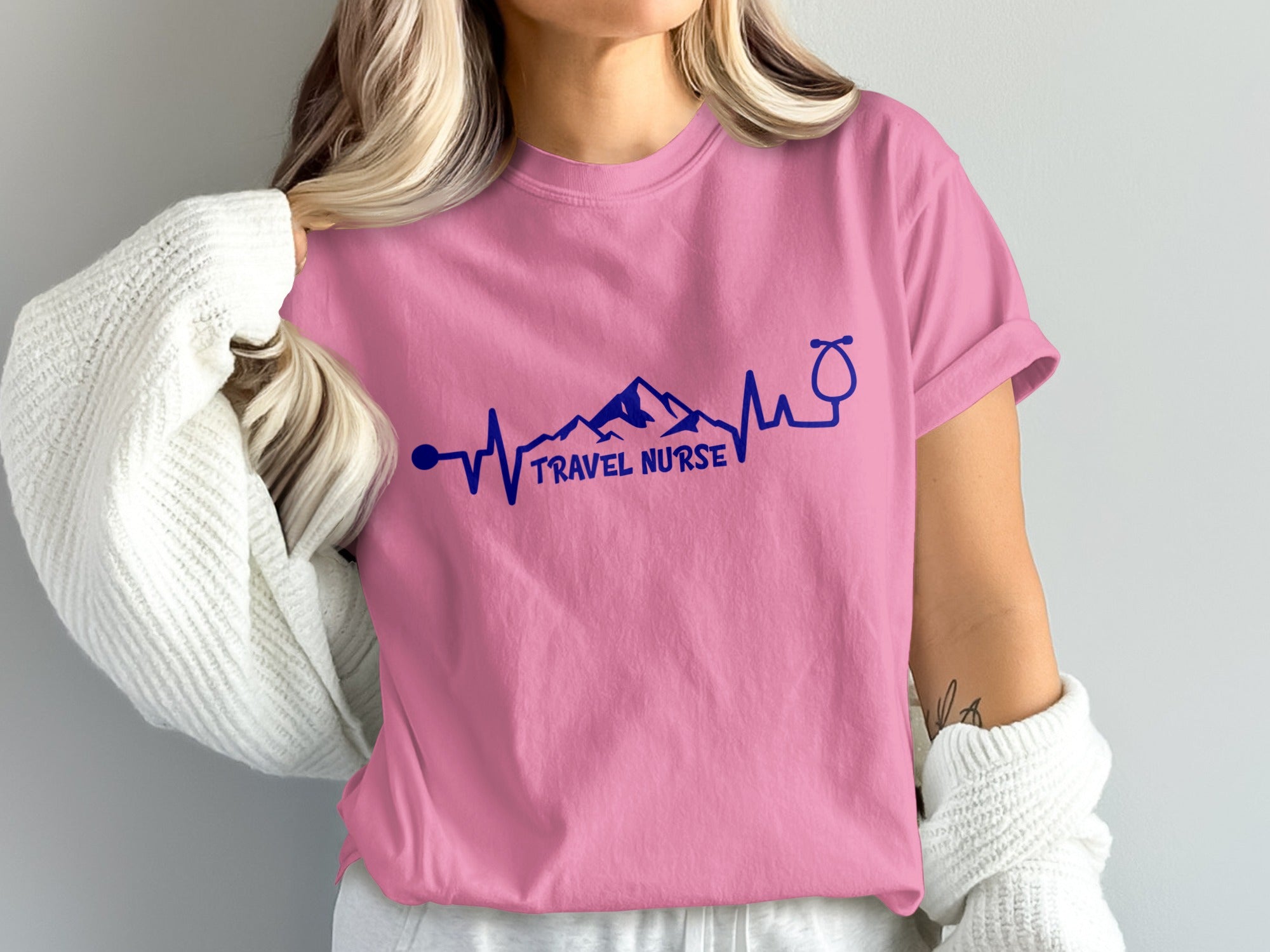 Pink t-shirt with "Travel Nurse" text, mountain range, and stethoscope heartbeat.
