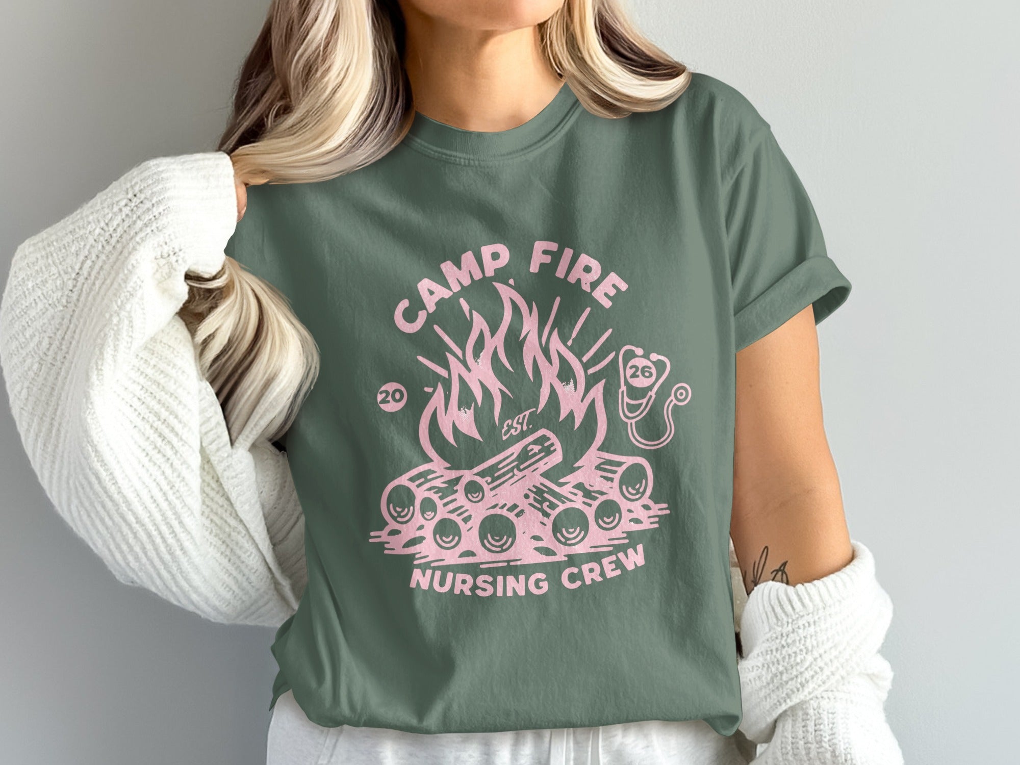 Camp Fire Nursing Crew graphic on a green t-shirt with pink flames and logs.