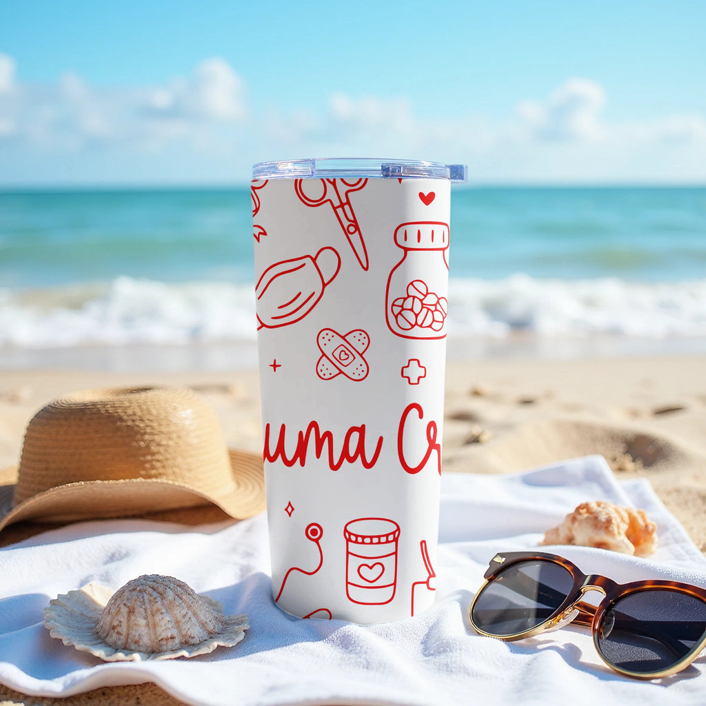 White tumbler with medical icons on a beach with sunglasses and a hat.