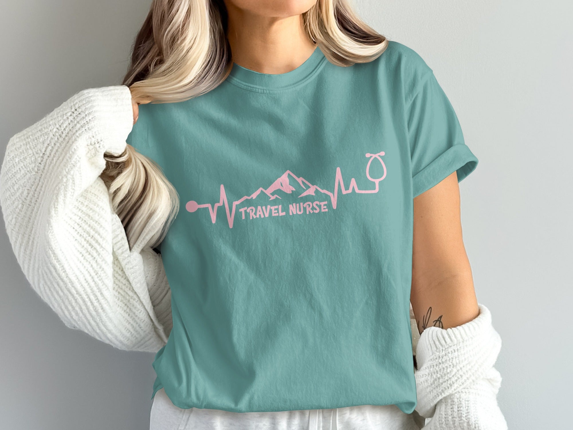 Teal t-shirt with pink stethoscope and mountain heart monitor graphic and "TRAVEL NURSE" text.