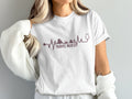 White t-shirt with "TRAVEL NURSE" text, desert landscape, and stethoscope.