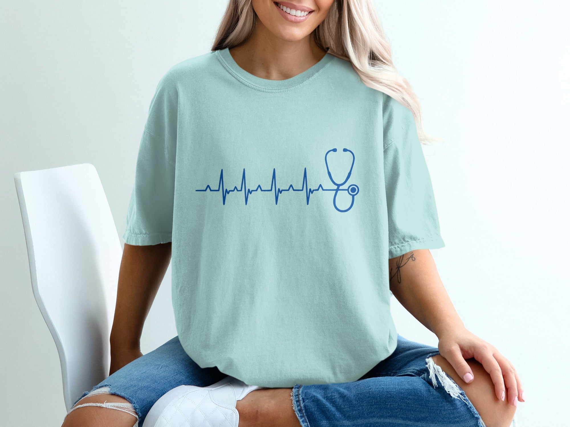 Light blue t-shirt with a blue electrocardiogram and stethoscope graphic.