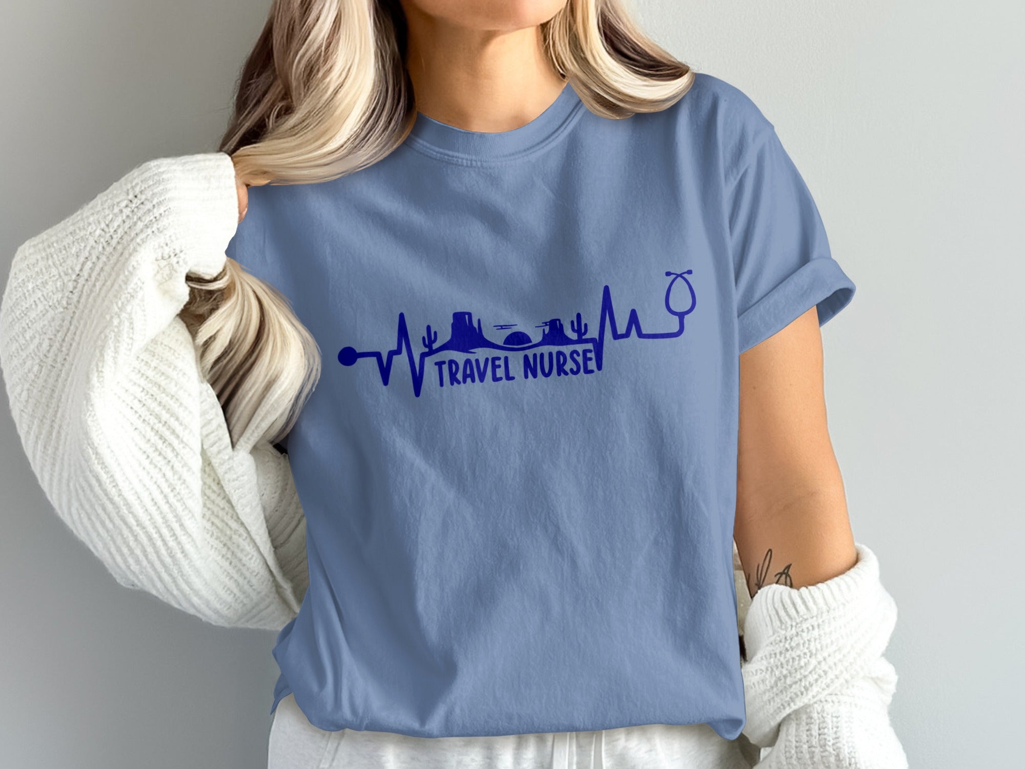 Blue t-shirt with heartbeat line graphic featuring desert mountains, palm trees, and a stethoscope.
