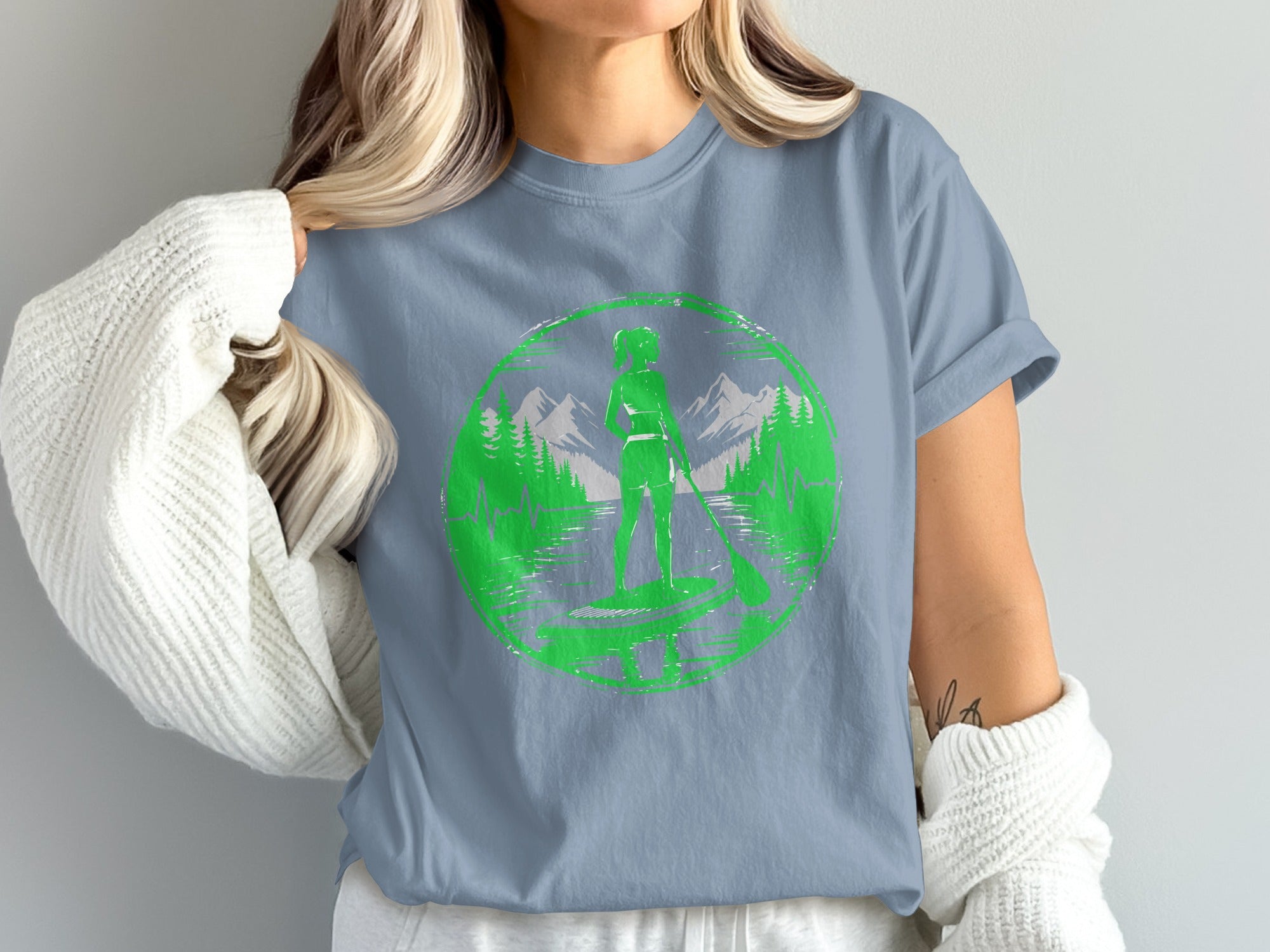 Green circular graphic of a paddleboarder with mountains and trees.