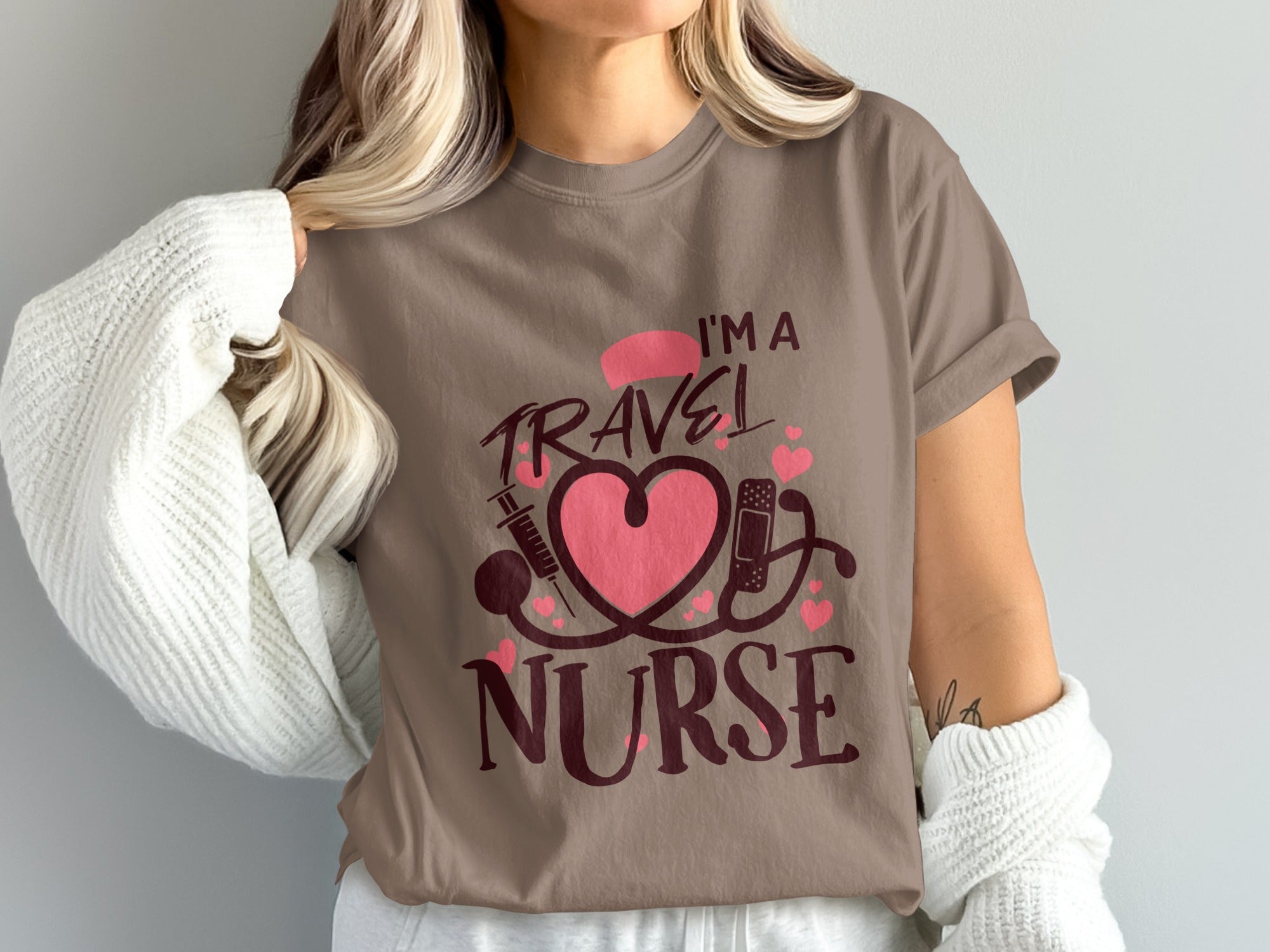 Brown t-shirt with pink "I'm a Travel Nurse" text and medical symbols.