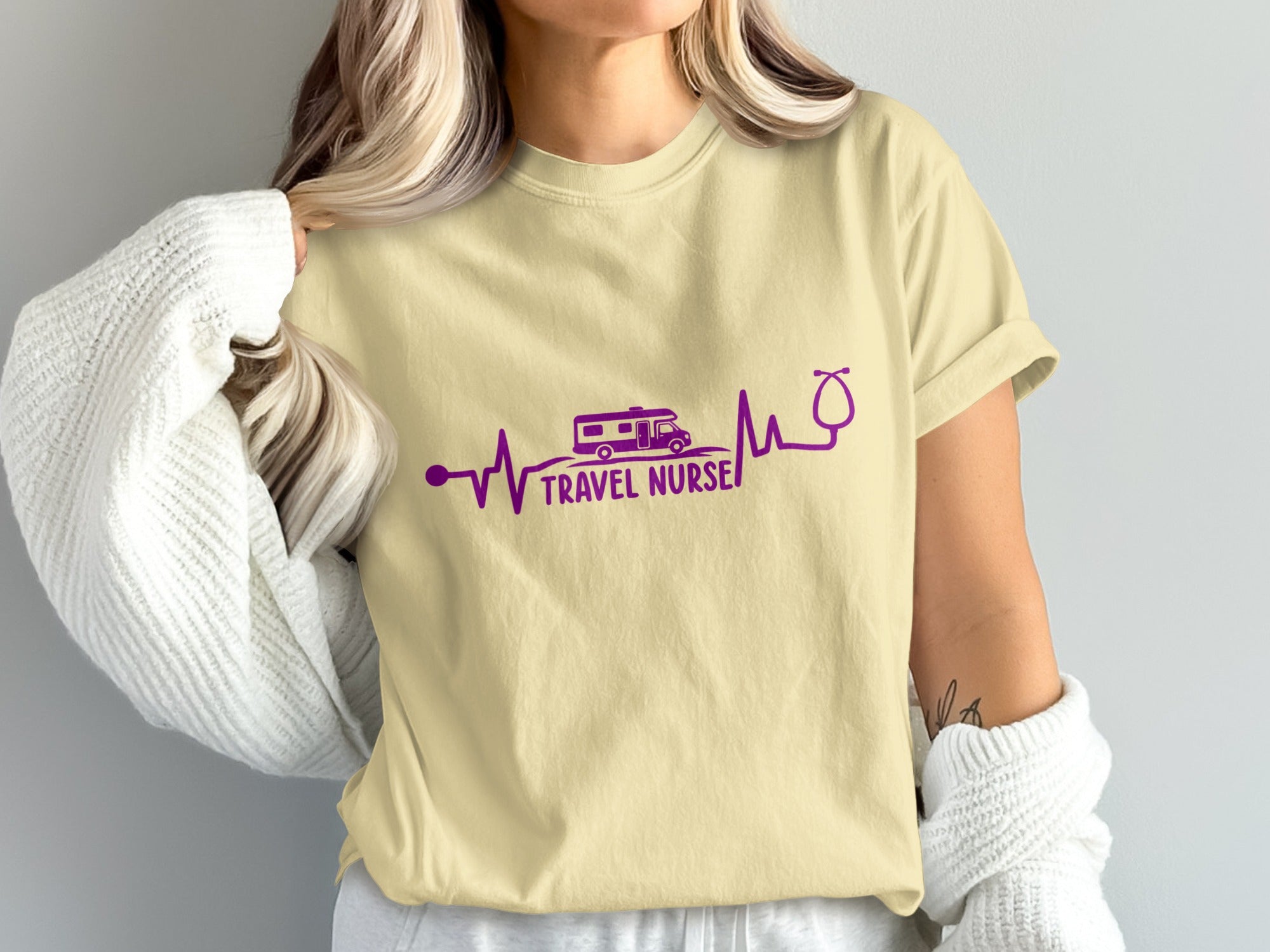 Cream t-shirt with purple heartbeat graphic, RV, and stethoscope, reading "TRAVEL NURSE."